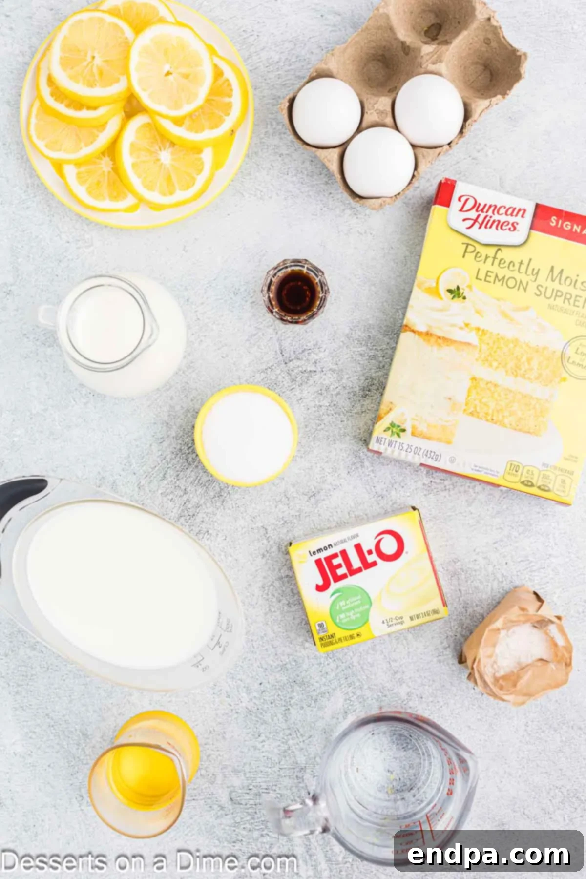 Ingredients laid out for making a Lemon Trifle dessert, including a lemon cake mix box, oil, eggs, instant pudding mix, milk, heavy whipping cream, and vanilla extract.