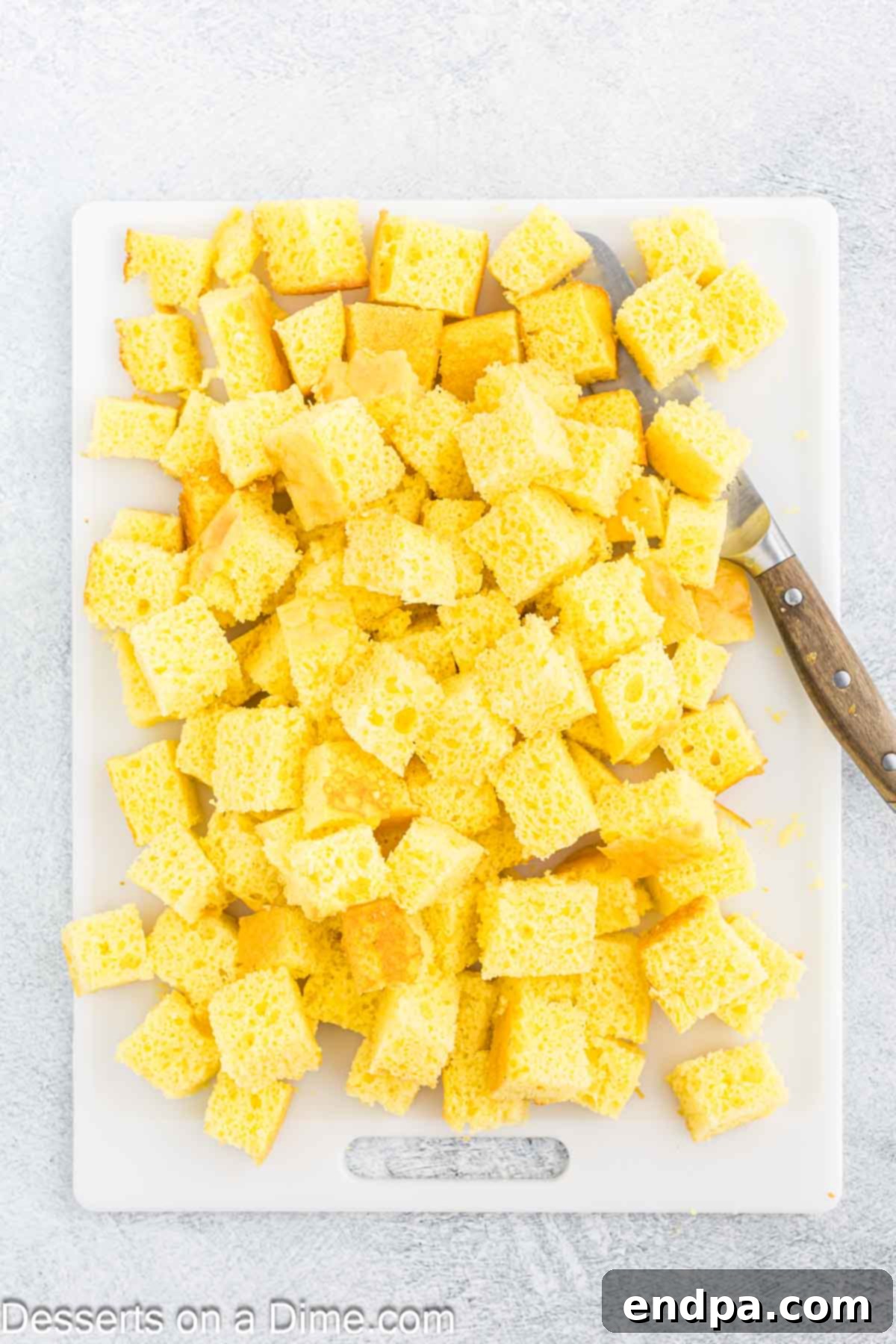 Cooled lemon cake neatly cut into bite-sized cubes, ready for layering in the trifle dish.