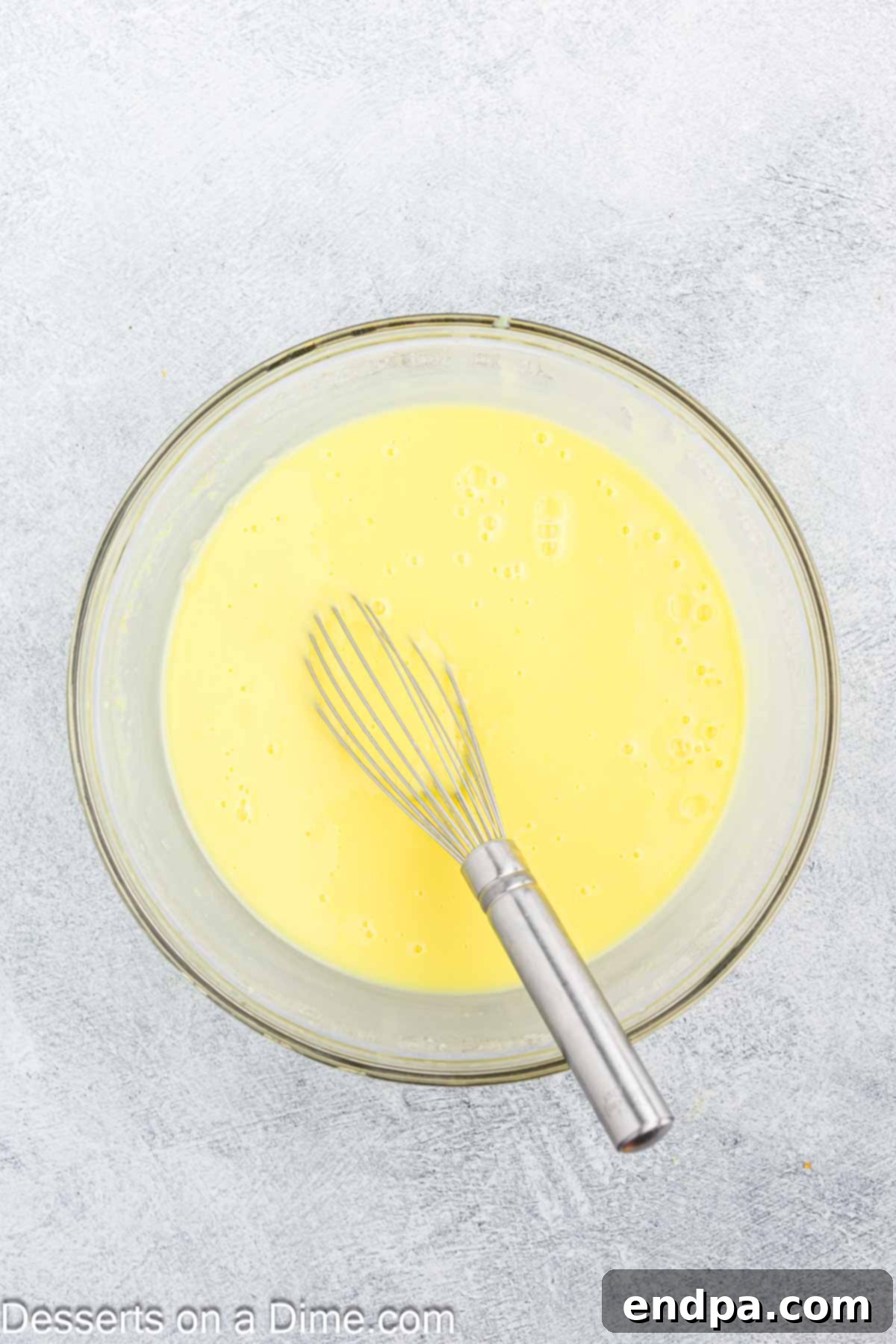 Smooth, creamy lemon pudding mixture in a large mixing bowl, recently whisked.