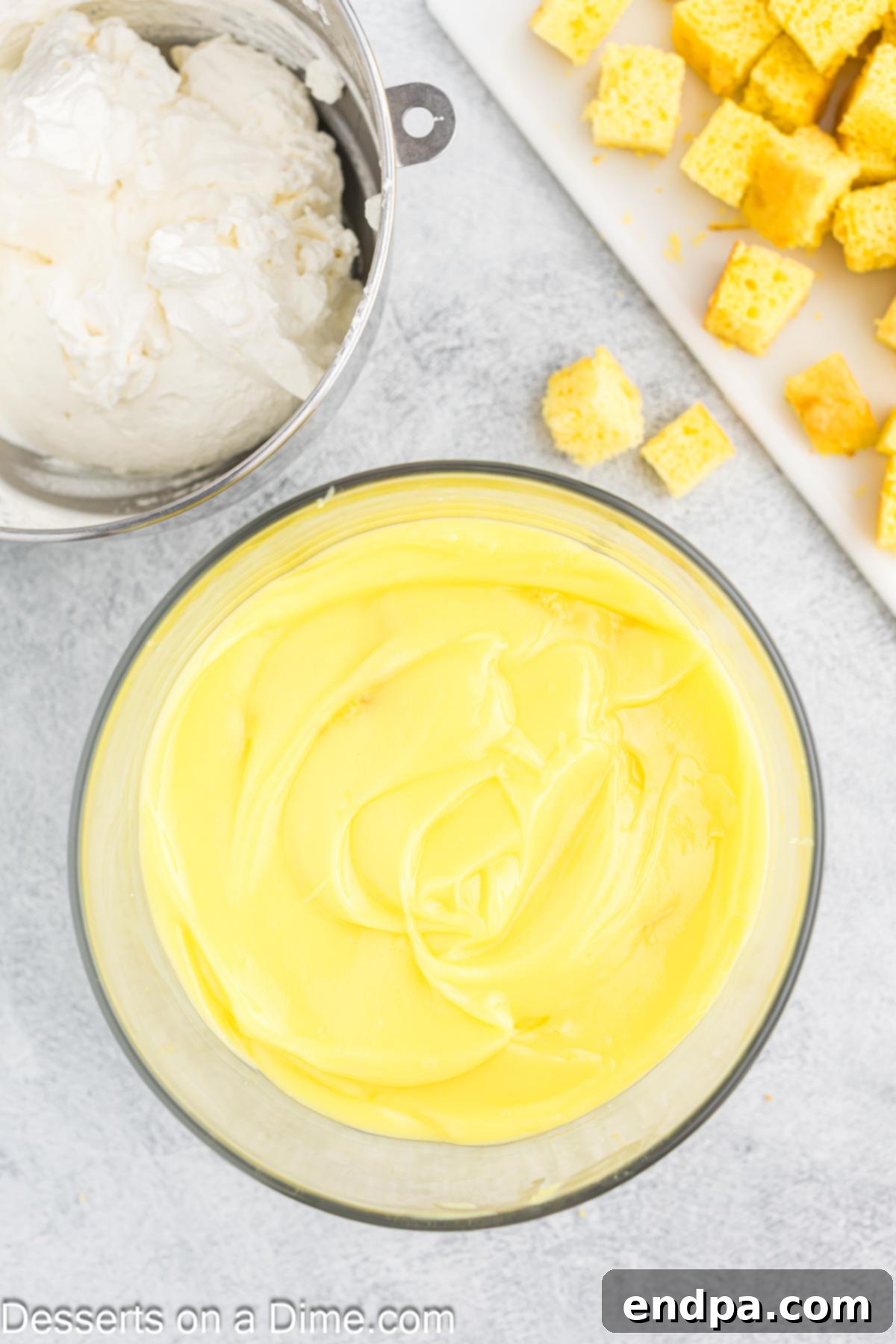 The lemon pudding layer spread smoothly over the cubed lemon cake in the trifle dish.