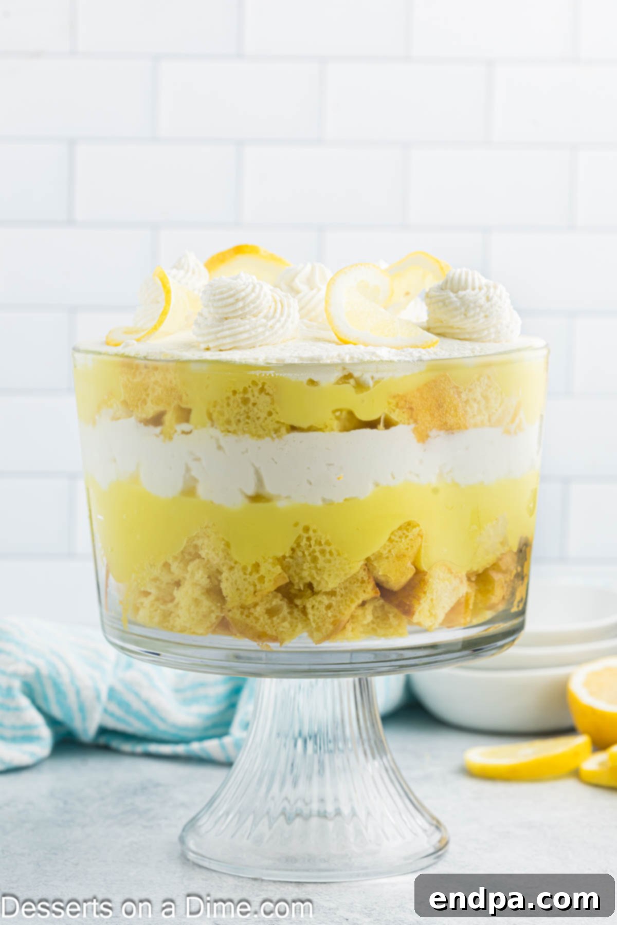 A beautifully layered lemon trifle showing multiple layers of cake, pudding, and whipped cream, ready for its final garnish.