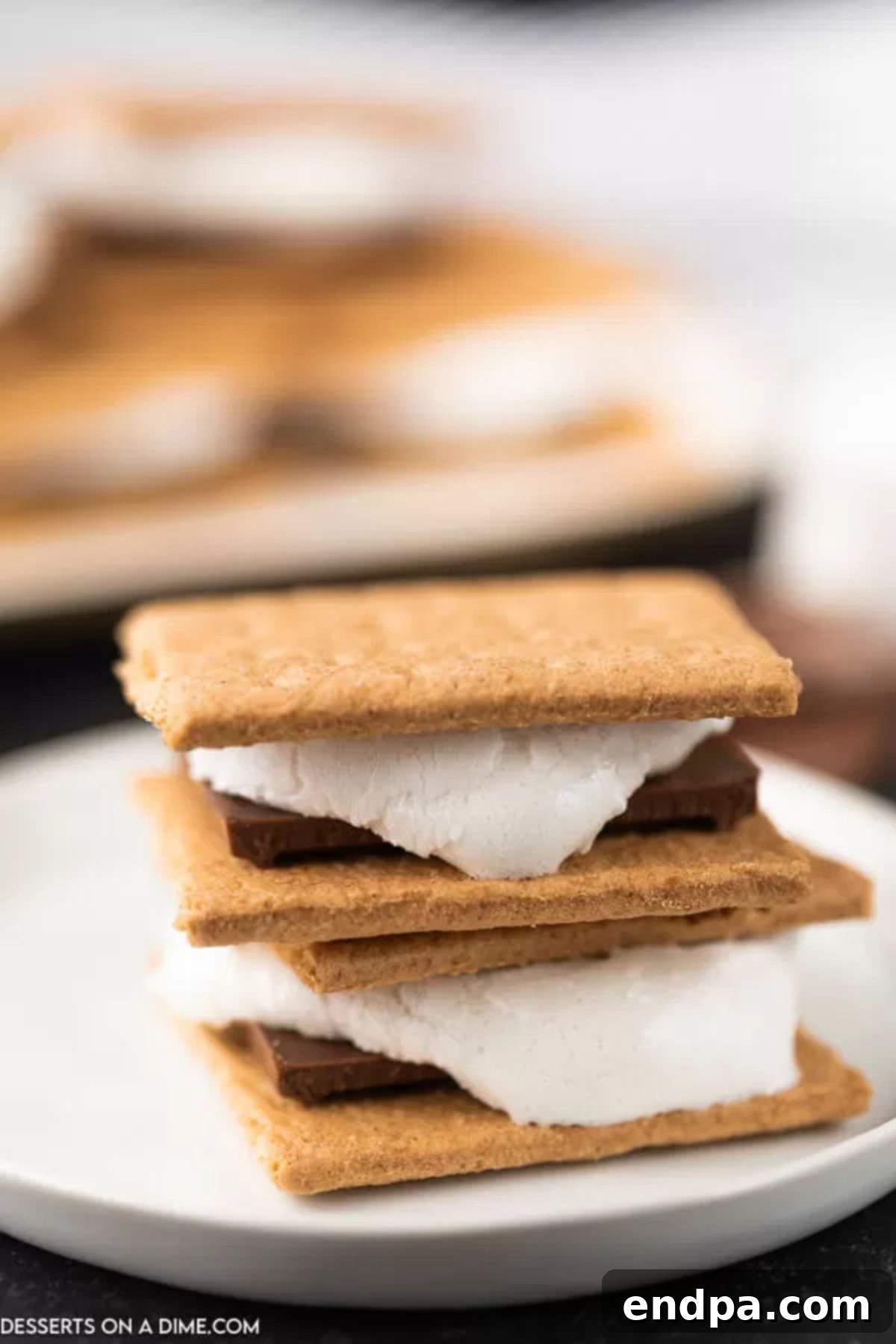 Oven baked smores are so convenient and you still can enjoy all the ooey gooey marshmallows and decadent chocolate. Try oven smores. Smores stacked on a plate, showcasing gooey marshmallow and melted chocolate