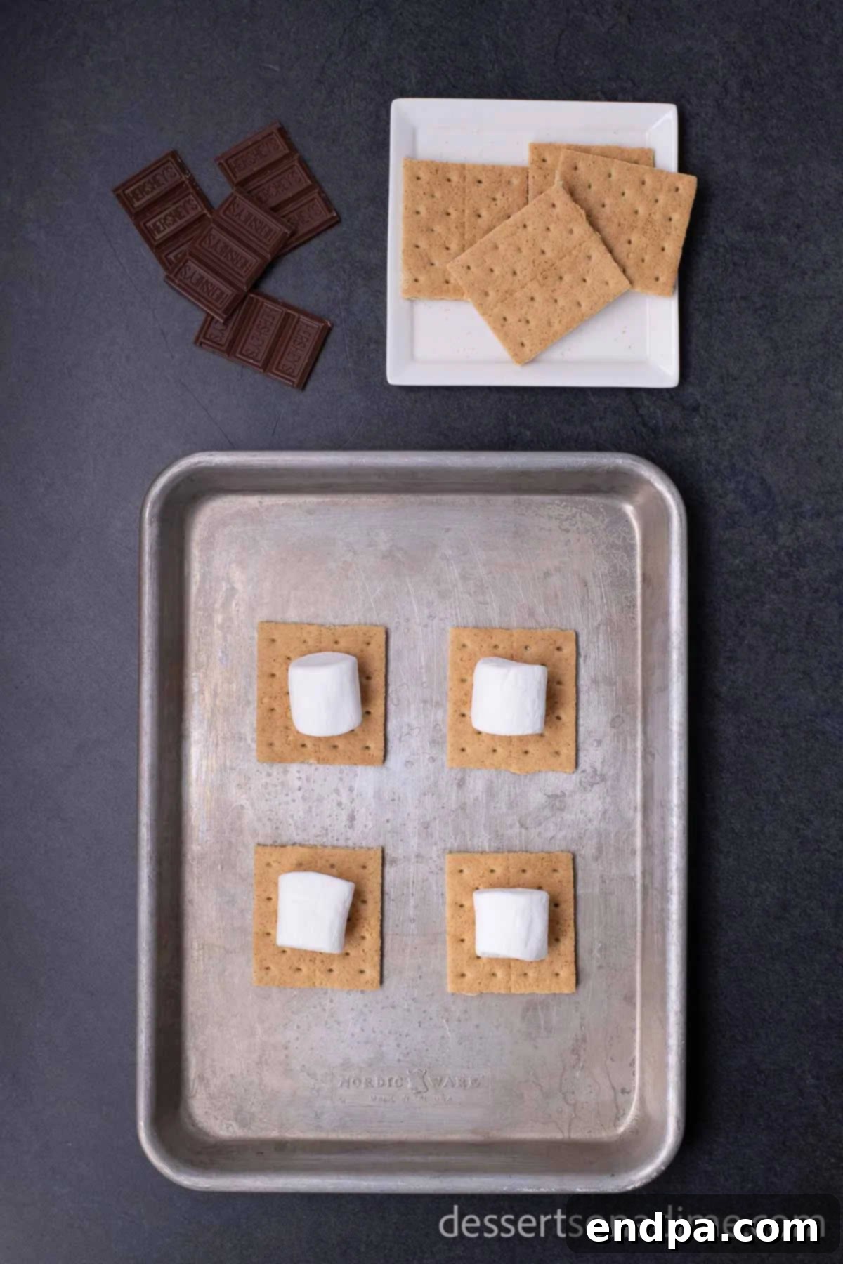 Perfect Oven S'mores: Your Campfire-Free Indulgence 3 Topping graham cracker halves with large marshmallows on a baking sheet