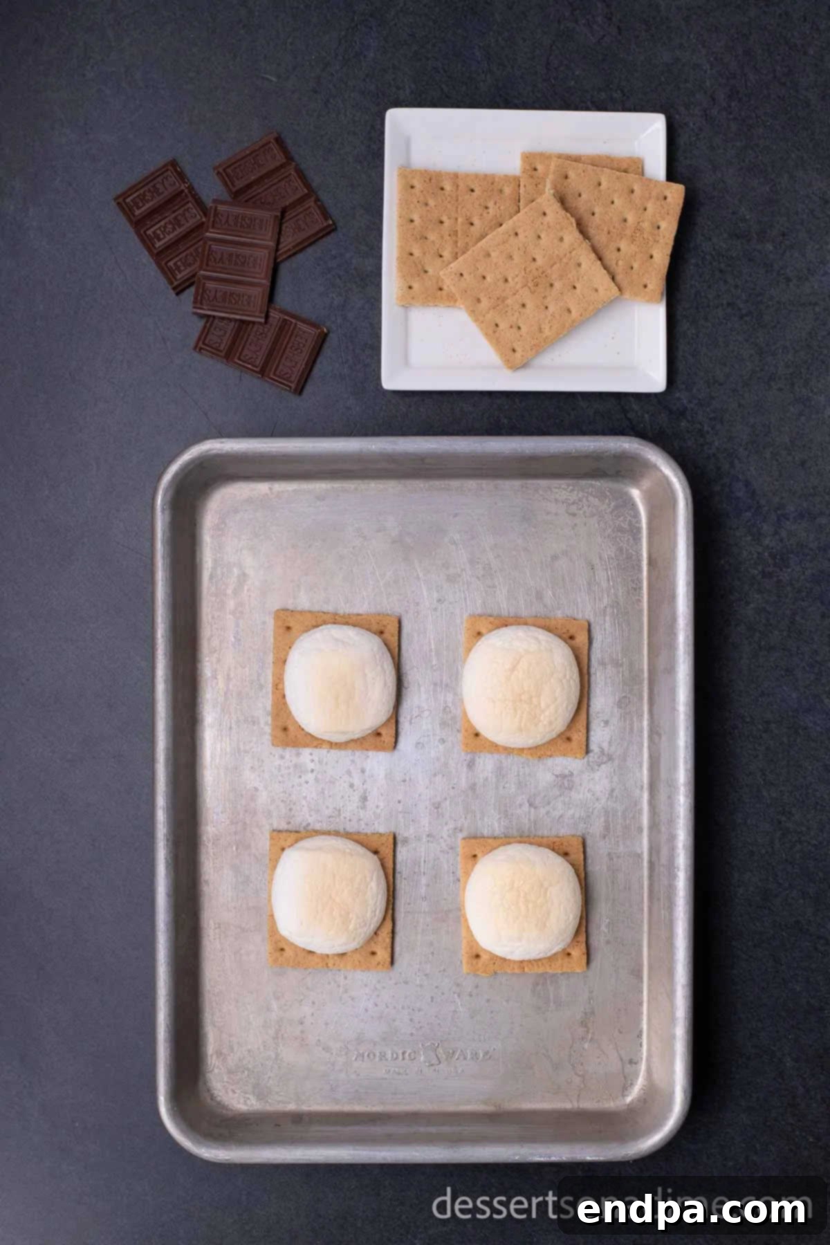 Perfect Oven S'mores: Your Campfire-Free Indulgence 4 Marshmallows roasted to a golden brown on graham cracker halves on a baking sheet