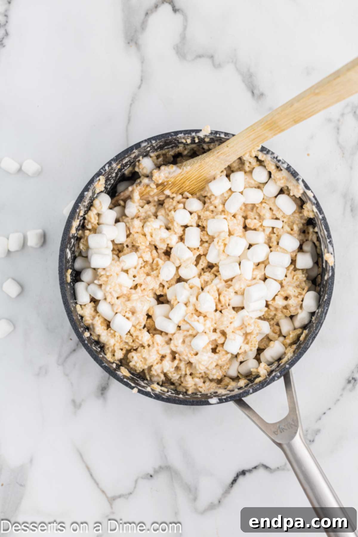 Rice Krispies cereal being stirred into the melted marshmallow mixture in a saucepan.