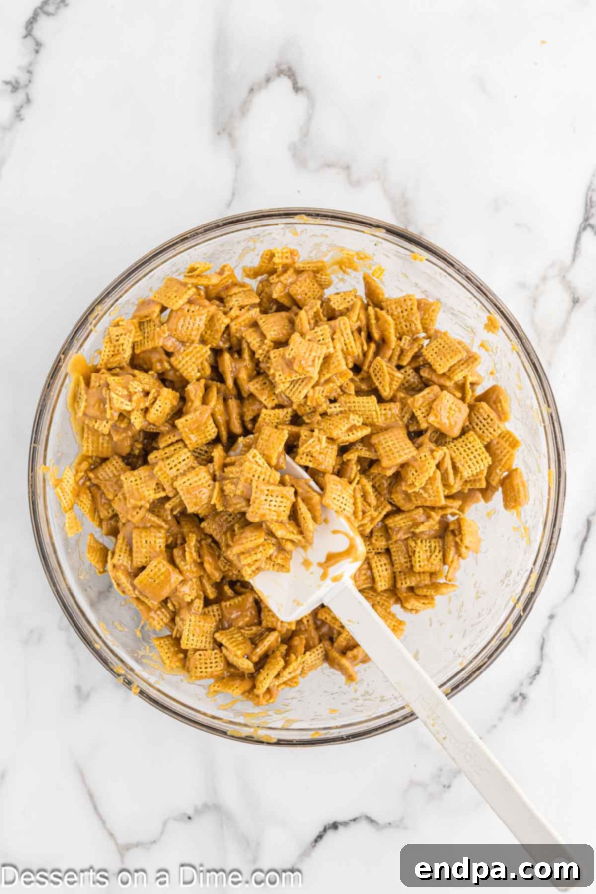 Chex Peanut Butterscotch Crunch 5 The warm peanut butter mixture being poured over Chex cereal in a large mixing bowl.