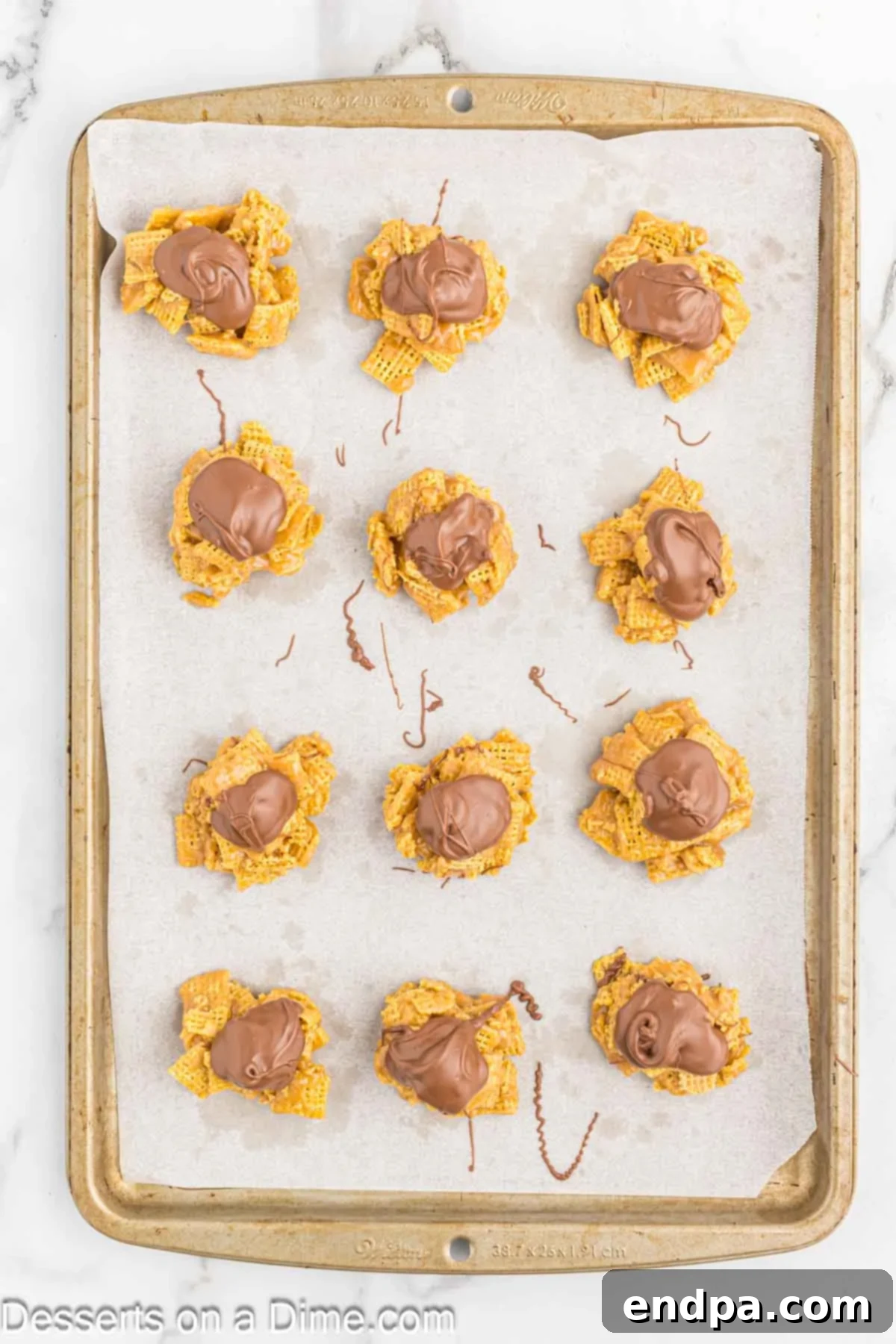 Chex Peanut Butterscotch Crunch 8 Chex Scotcheroos clusters on a baking sheet, freshly topped with melted chocolate and butterscotch, waiting to cool and set.