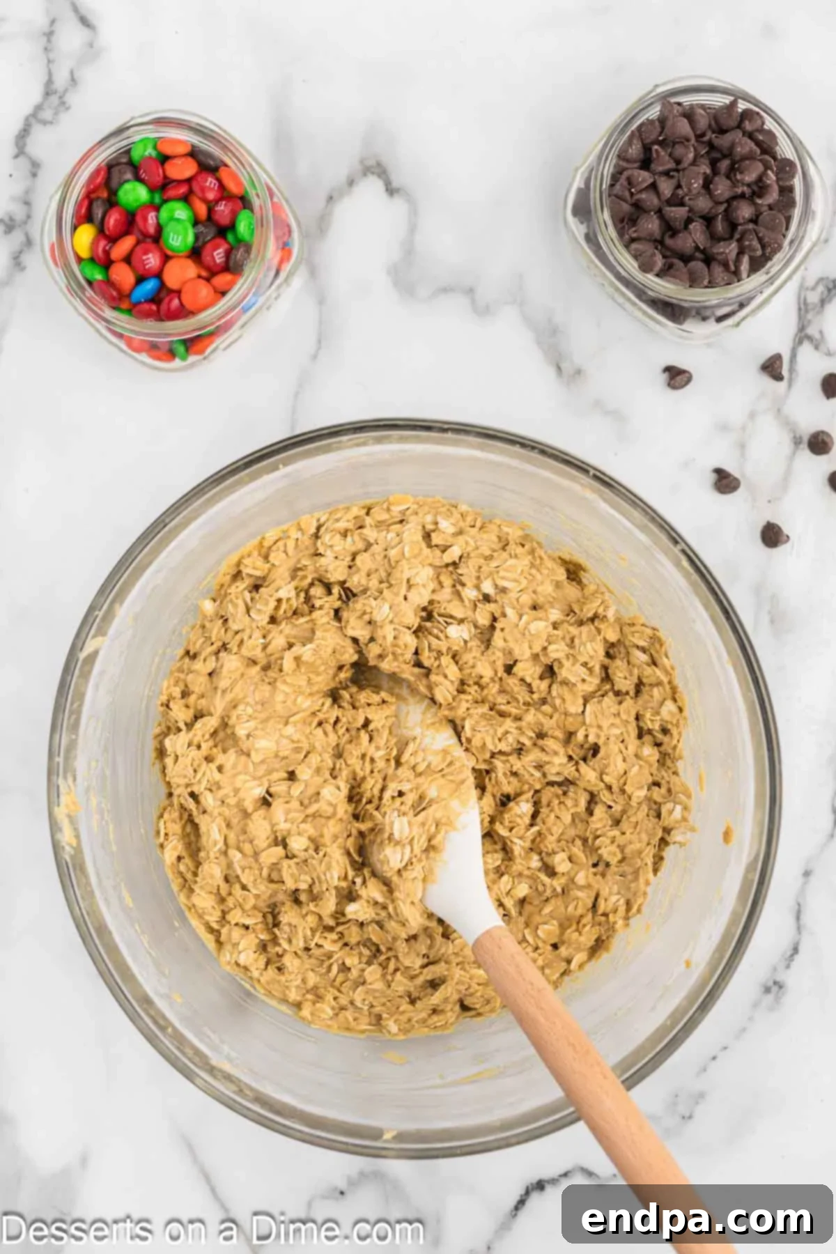 Old-fashioned rolled oats being added to the creamy cookie dough mixture.