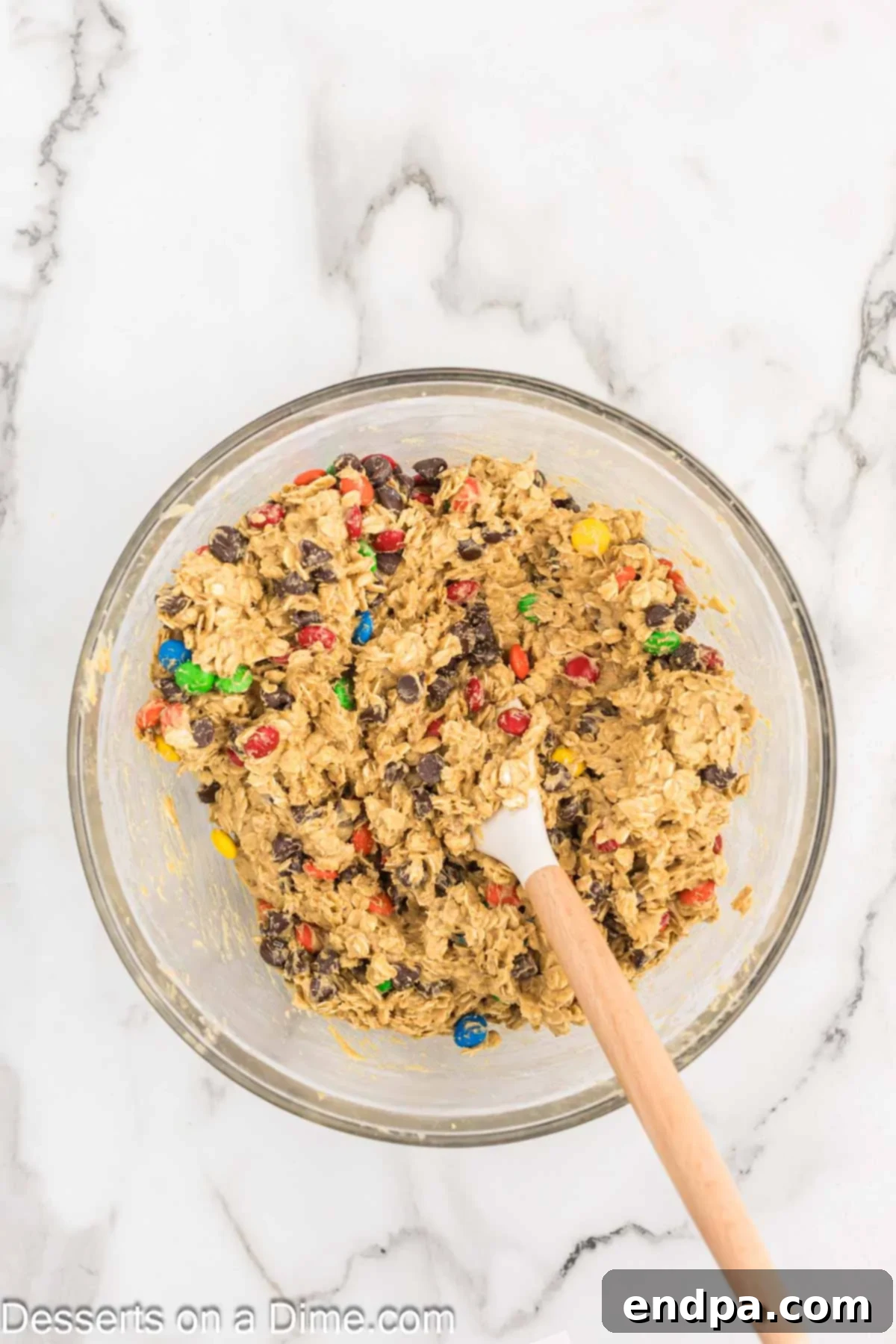 Colorful M&M's and chocolate chips being folded into the cookie dough.