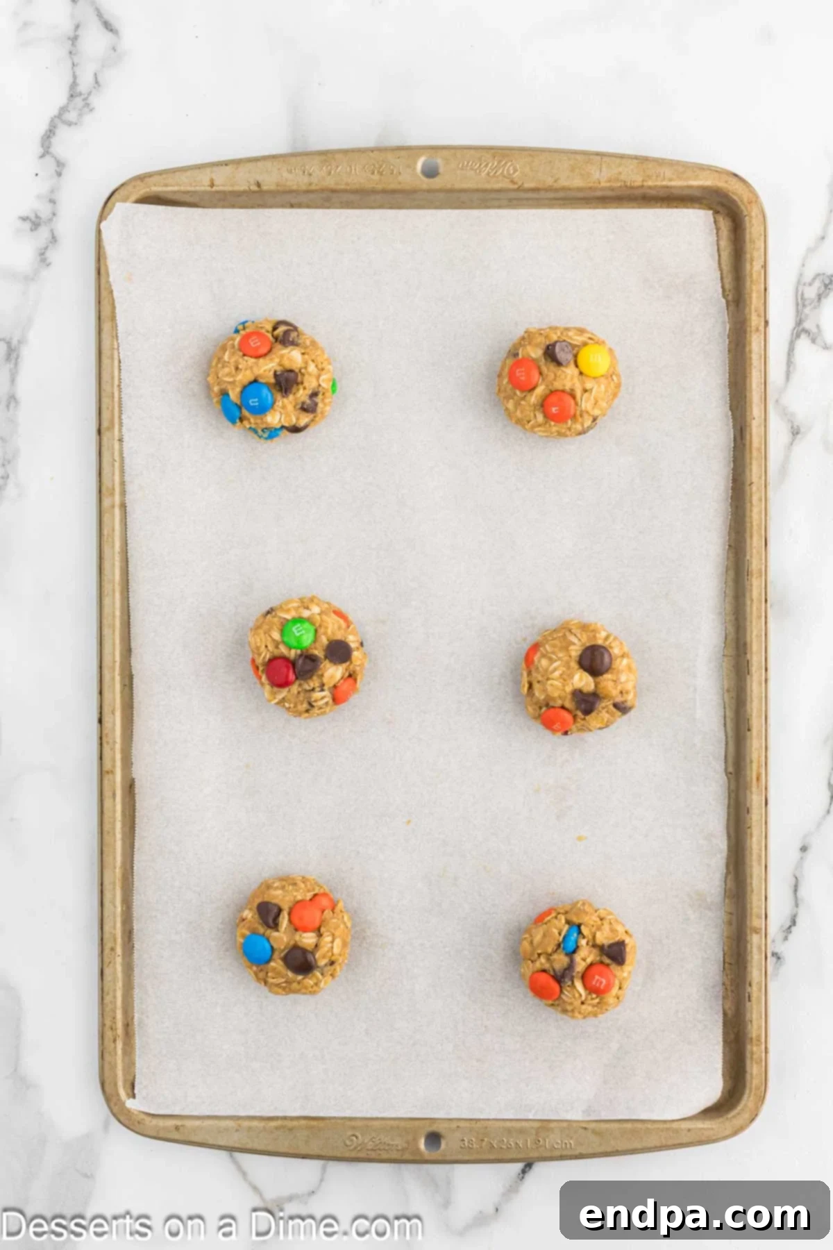 Scooped cookie dough balls placed on a parchment-lined baking sheet, ready for the oven.