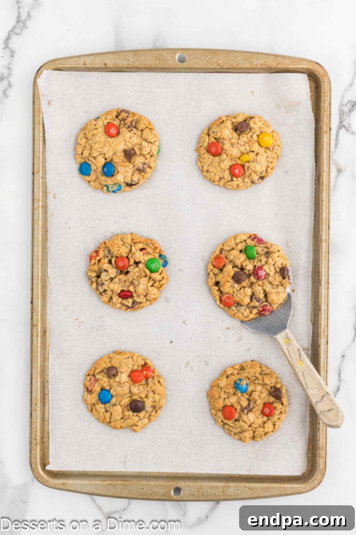 Freshly baked Monster Cookies cooling on the baking sheet, with slightly browned edges.