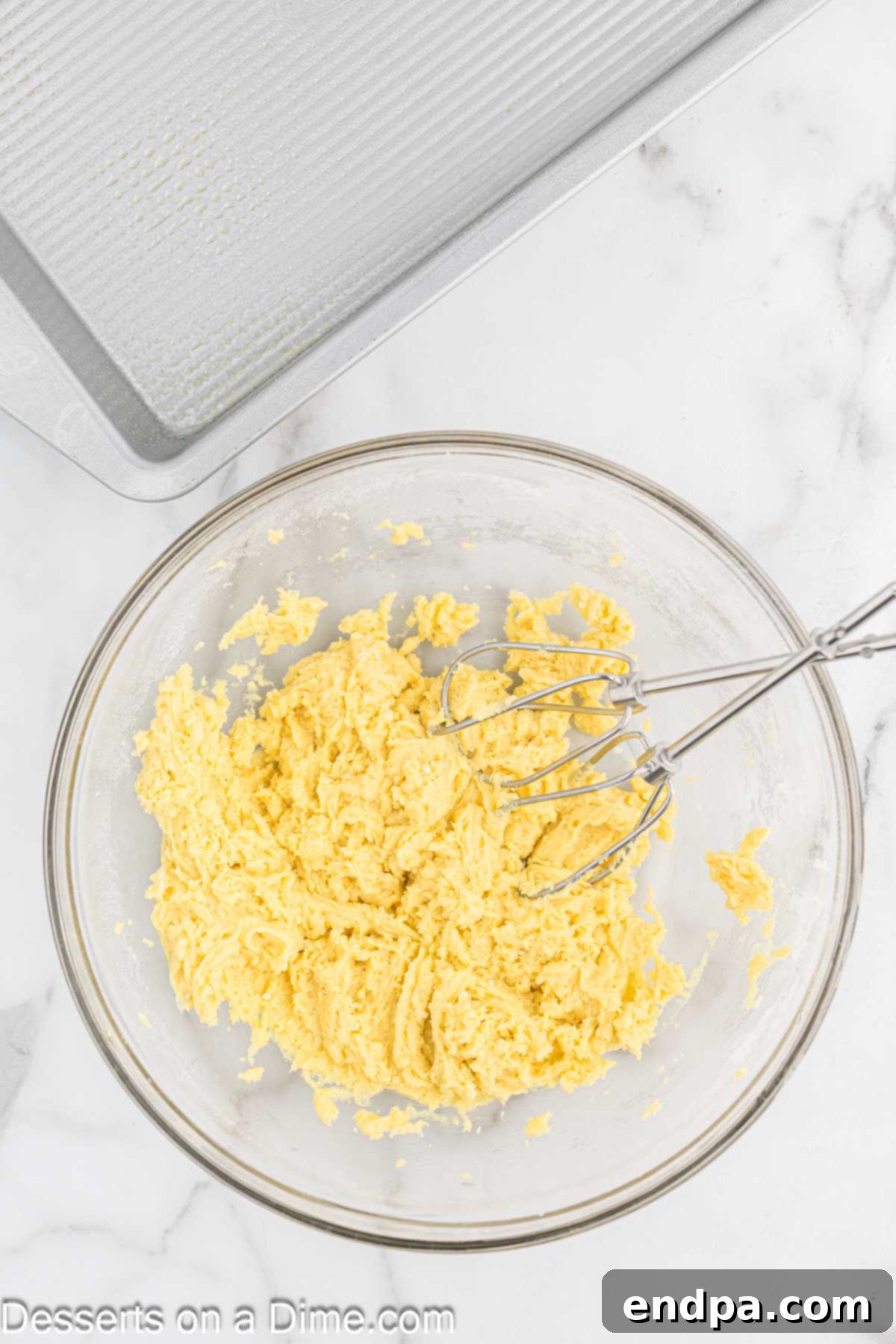 Cake mix ingredients combined in a mixing bowl, showing the yellow cake mix, melted butter, and egg forming a dough.