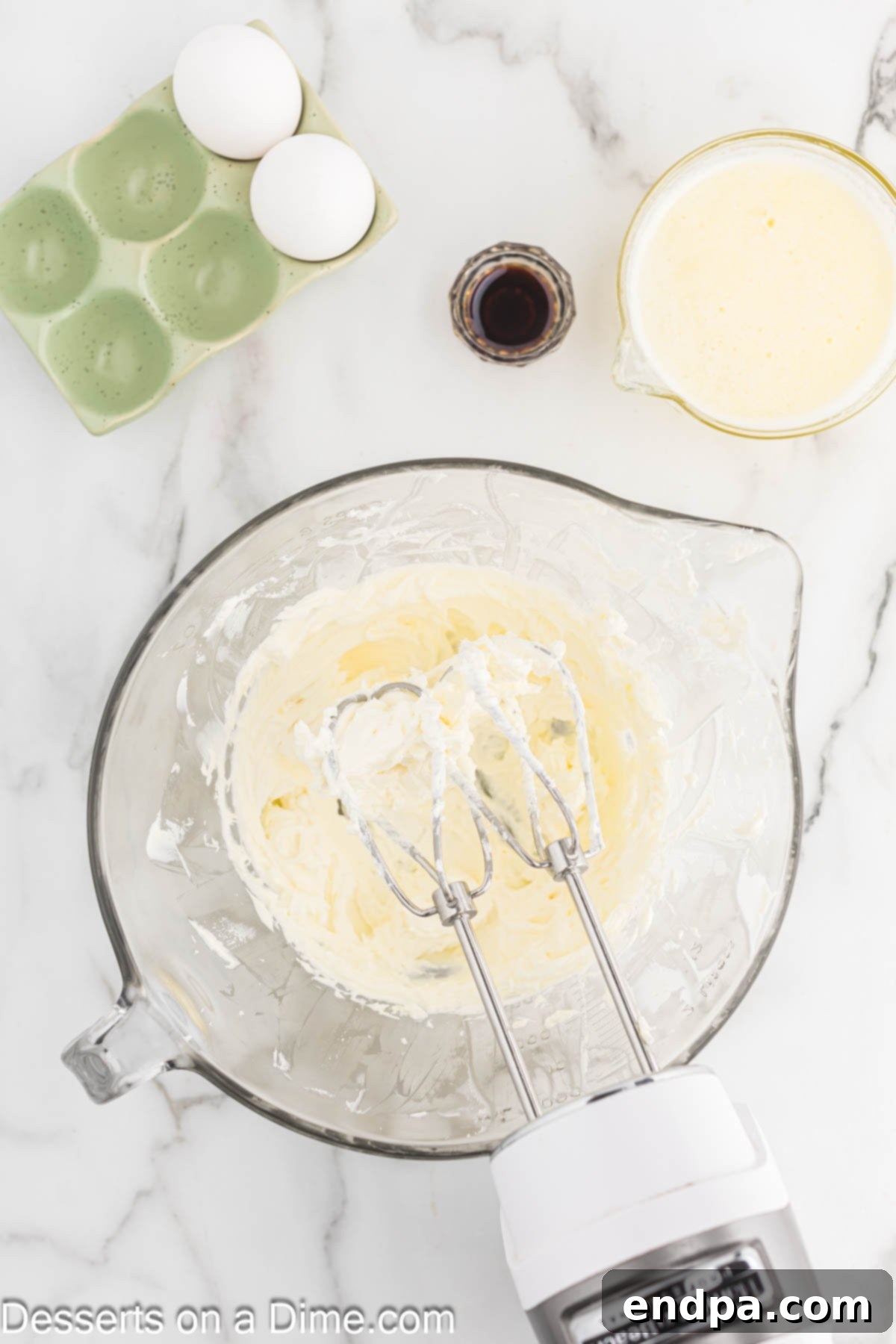 A mixing bowl with softened cream cheese being beaten until smooth and creamy with an electric mixer.