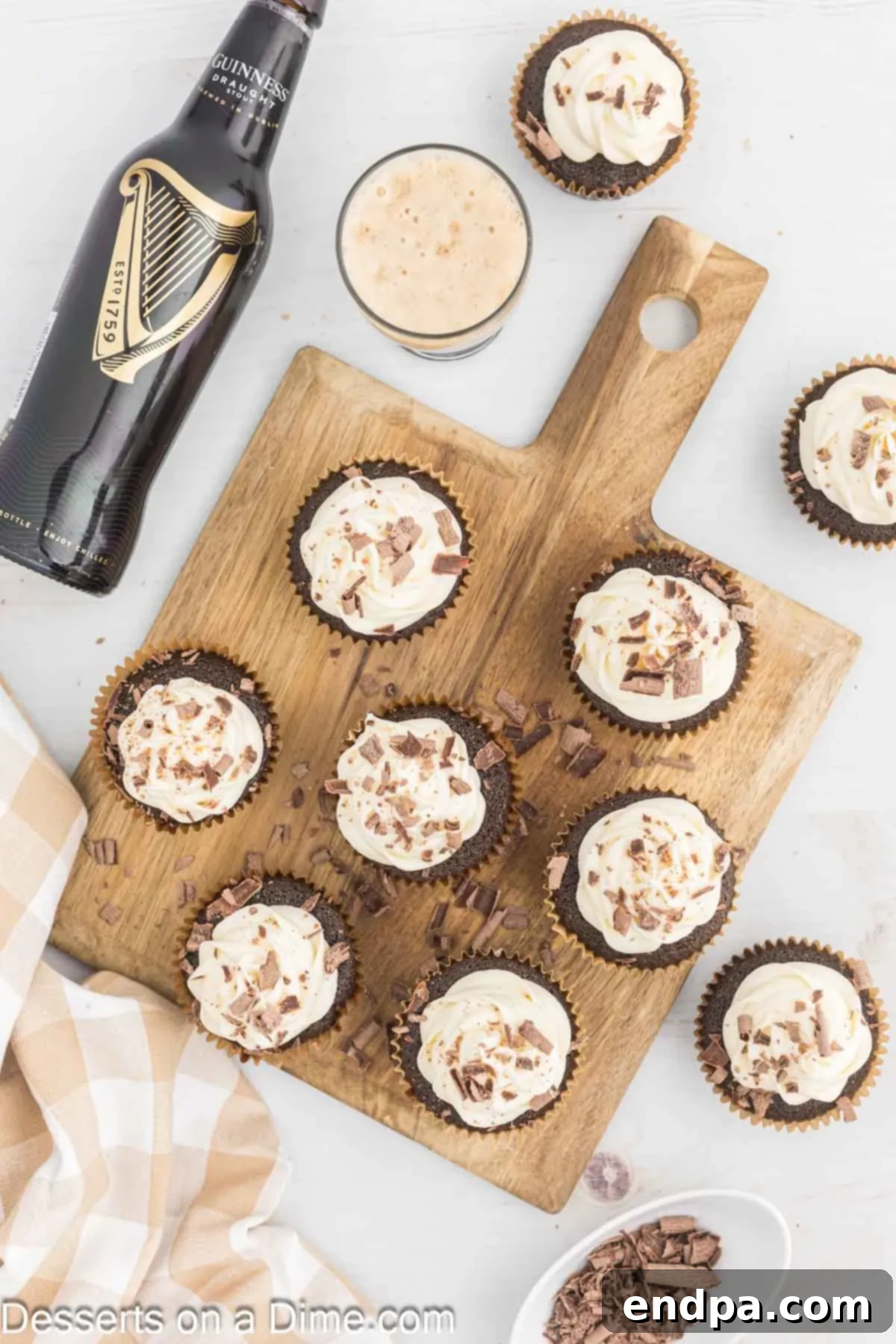 Guinness Cupcakes arranged on a wooden tray with a few garnished with chocolate shavings.