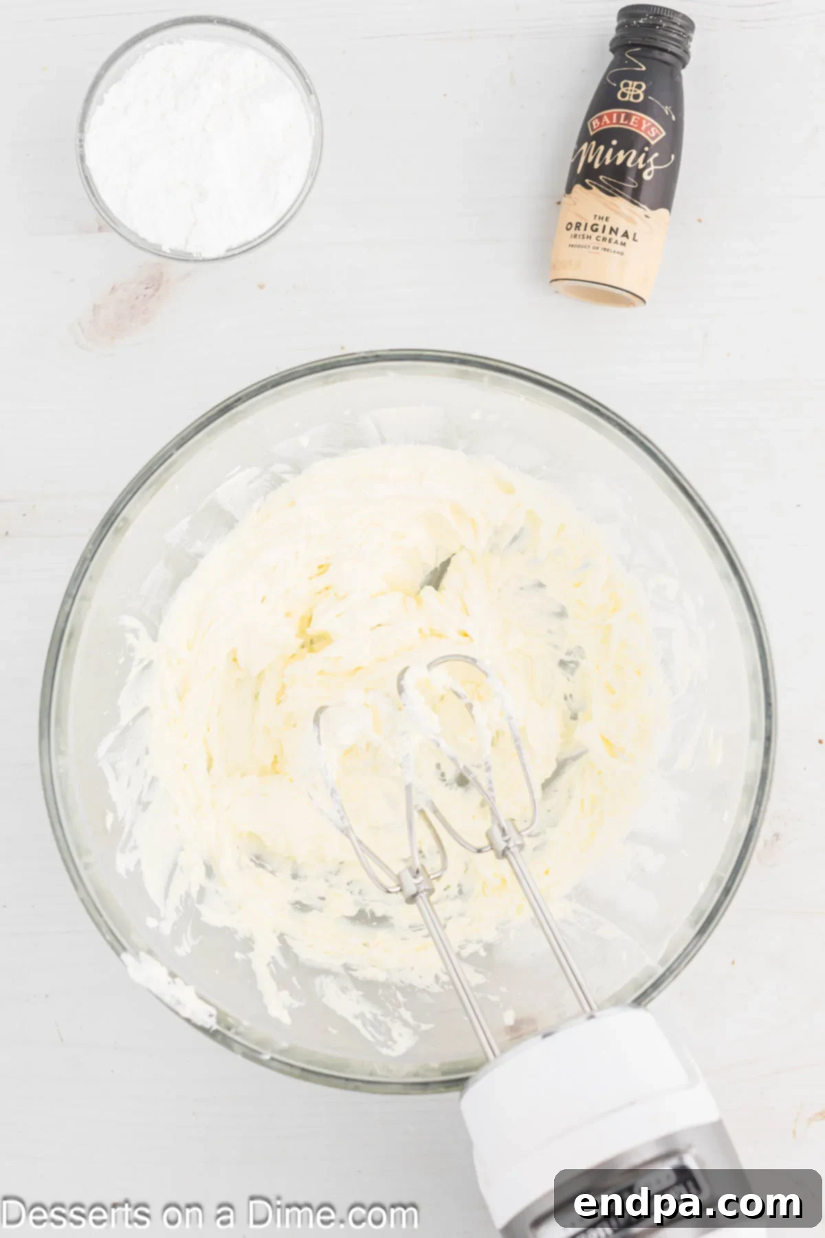Cream cheese and butter being beaten together in a mixing bowl for frosting.