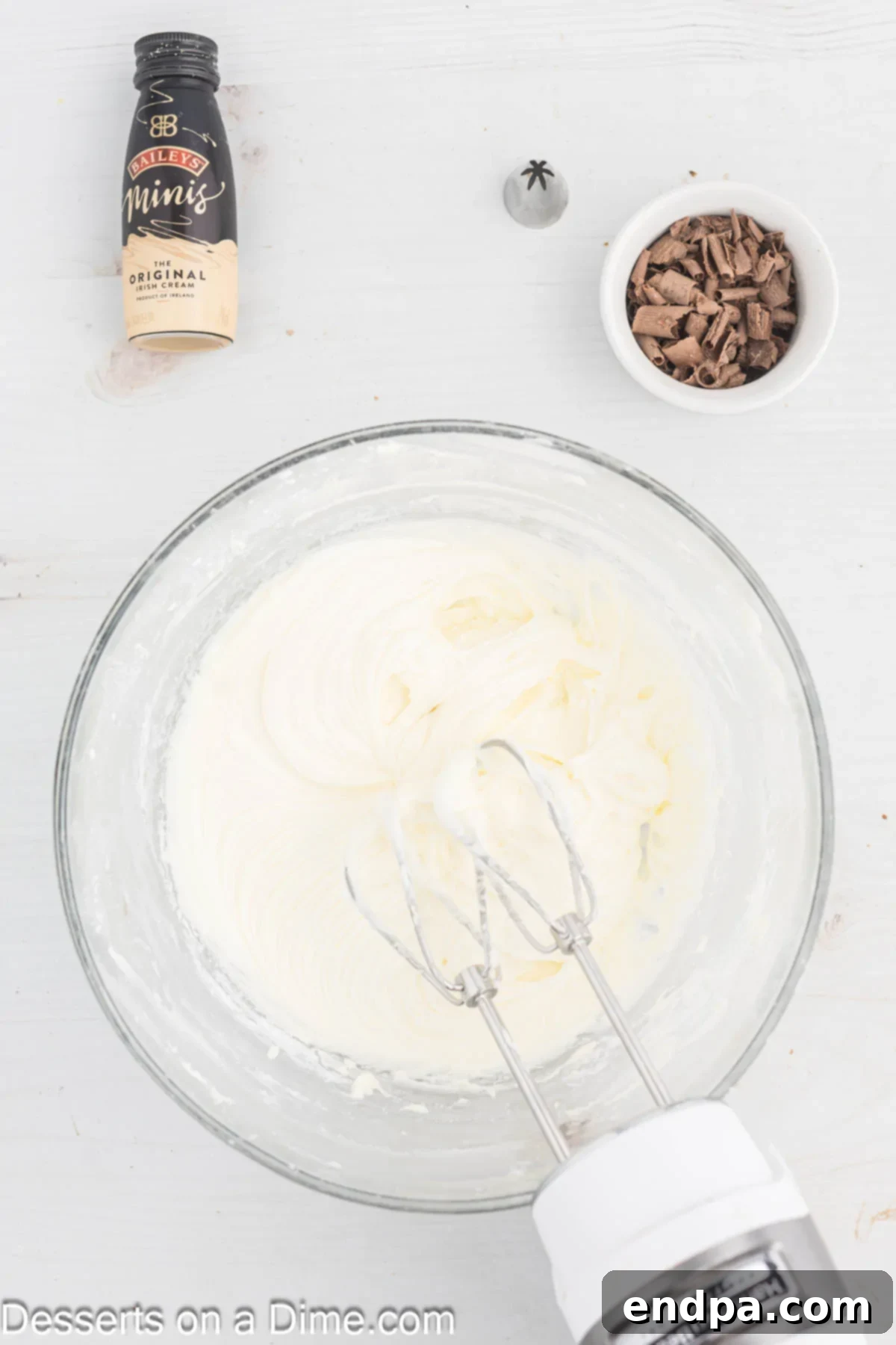 Powdered sugar and Bailey's Irish Cream being gradually added to the cream cheese frosting.