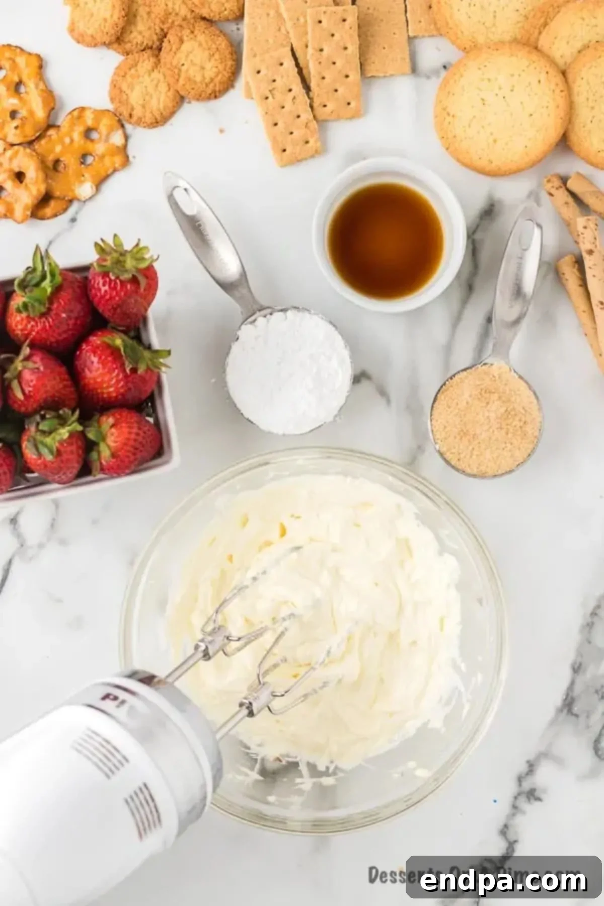 Heavenly Cheesecake Dip 4 Mixing bowl with cream cheese being beaten with a hand mixer until smooth.