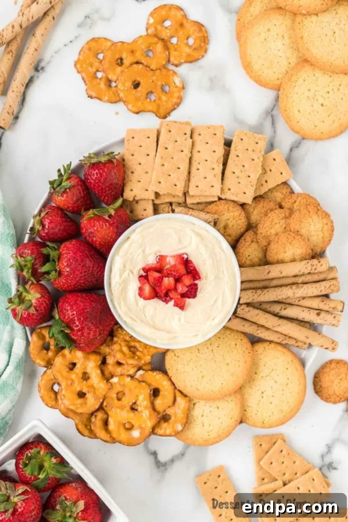 Heavenly Cheesecake Dip 7 A bowl of cheesecake dip surrounded by various dippers like fruit and cookies, ready to be served.