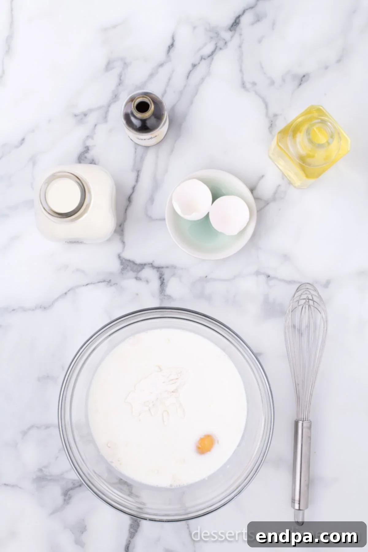 Crispy Cheesecake Indulgence 7 Egg, milk, vegetable oil, and vanilla extract being added to the pancake mix in a bowl.