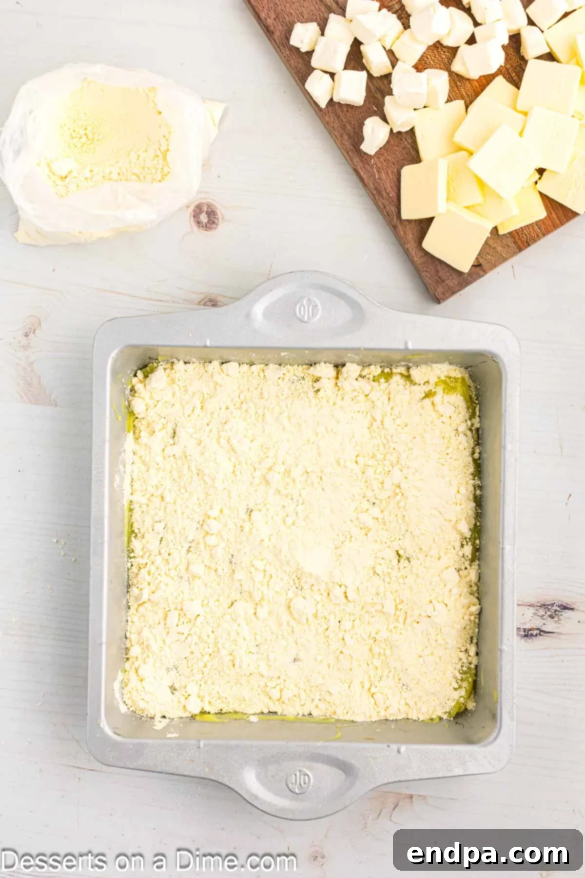 Zesty Lemon Easy Bake 6 Dry yellow cake mix being sprinkled by hand over a layer of lemon pie filling in a baking dish.