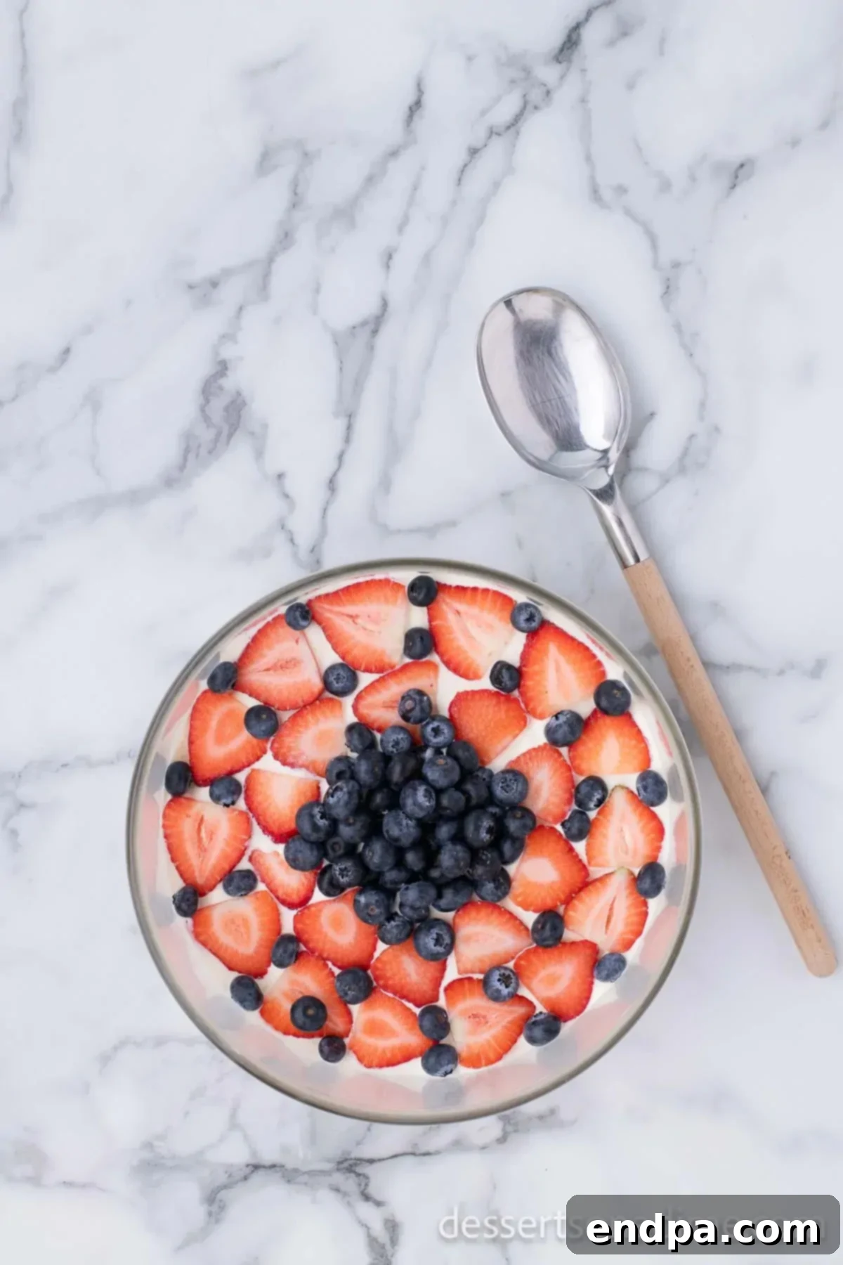 The top of the Red White and Blue Trifle, beautifully garnished with fresh strawberries and blueberries arranged in an attractive pattern.