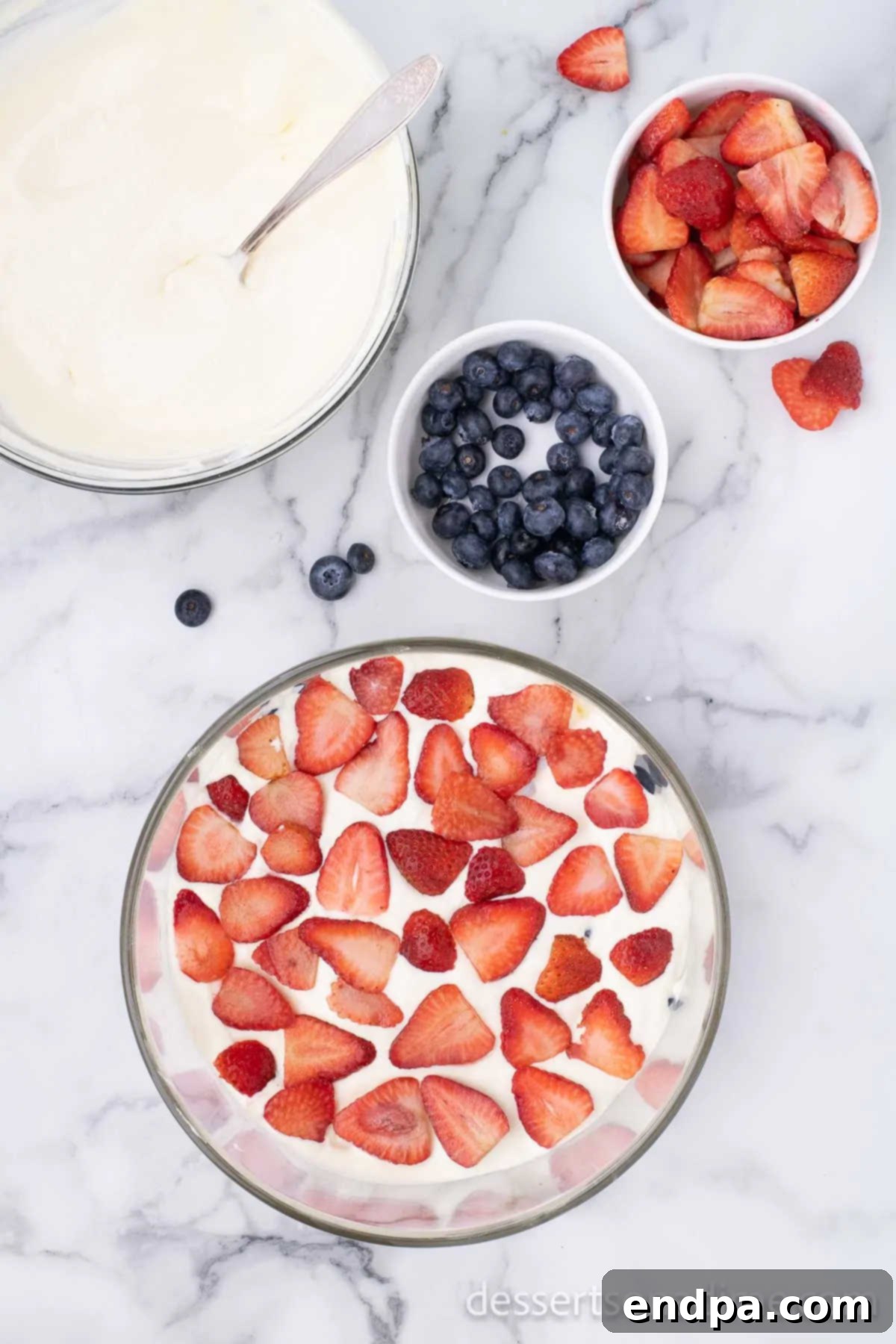 Fresh blueberries and sliced strawberries forming a vibrant layer in the trifle dish.