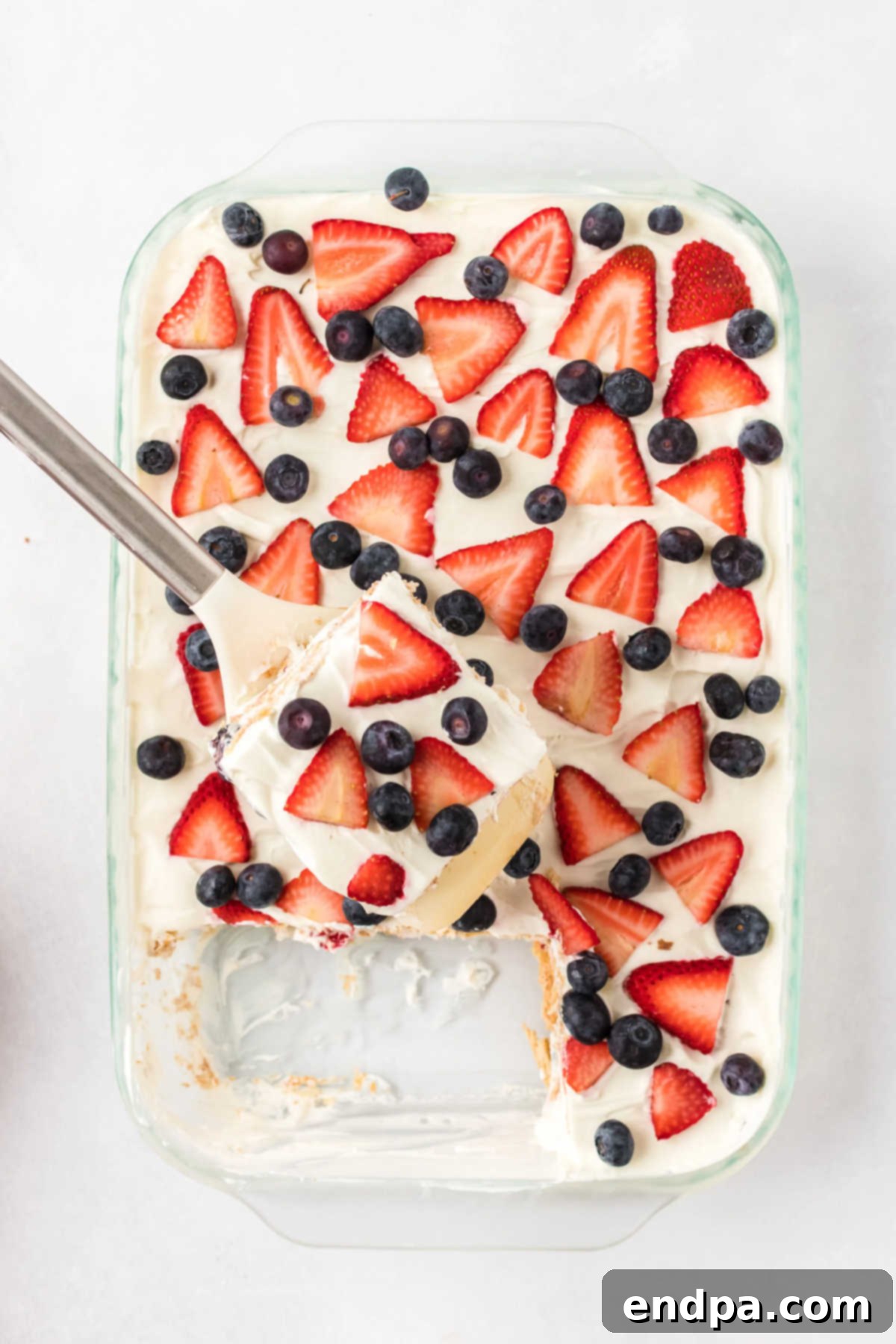 A spatula carefully lifts a slice of the Red White and Blue Icebox Cake from the baking dish, ready for serving.
