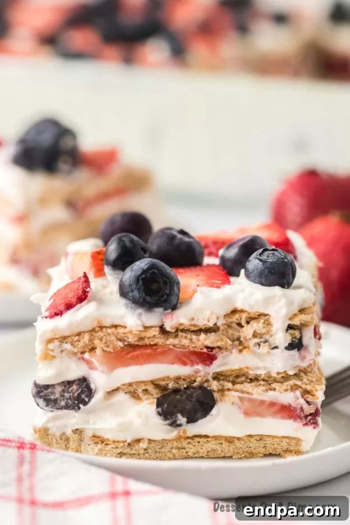 A perfectly portioned slice of Red White and Blue Icebox Cake on a white plate, showcasing its vibrant layers.