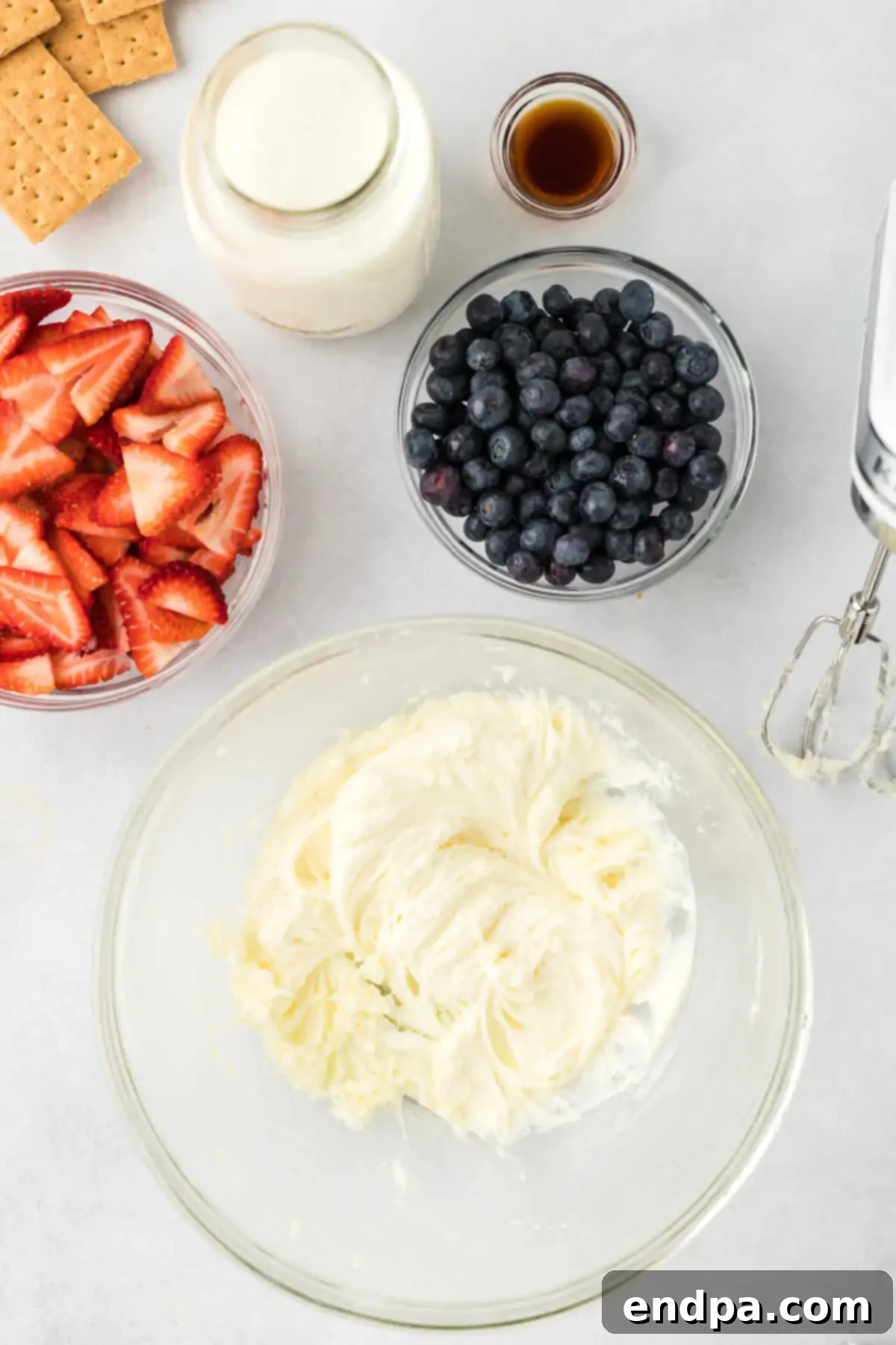 A mixing bowl filled with cream cheese and sugar being blended together until smooth and creamy.