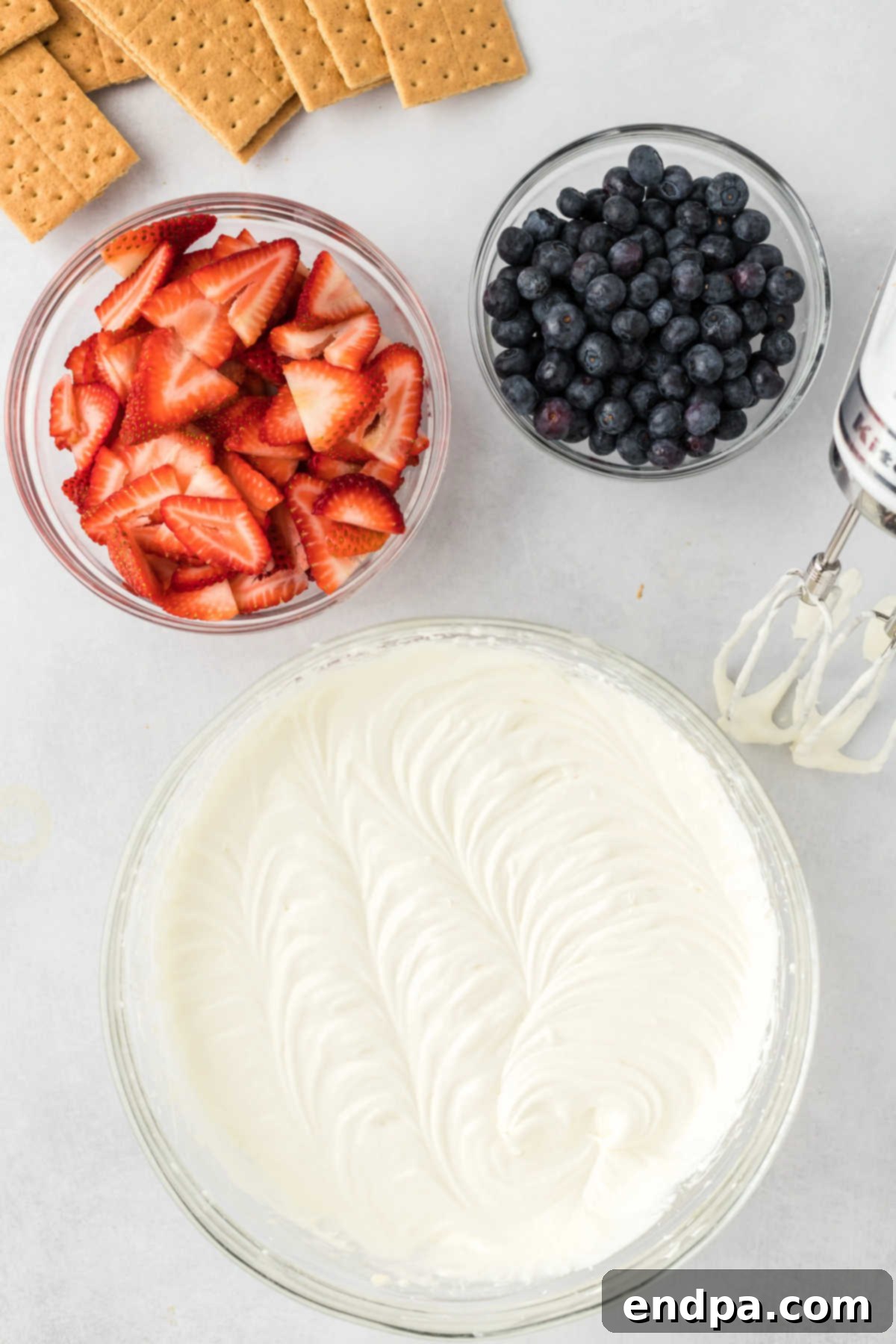 Heavy cream and vanilla extract are being added to the cream cheese mixture in a bowl, ready to be beaten until thickened.