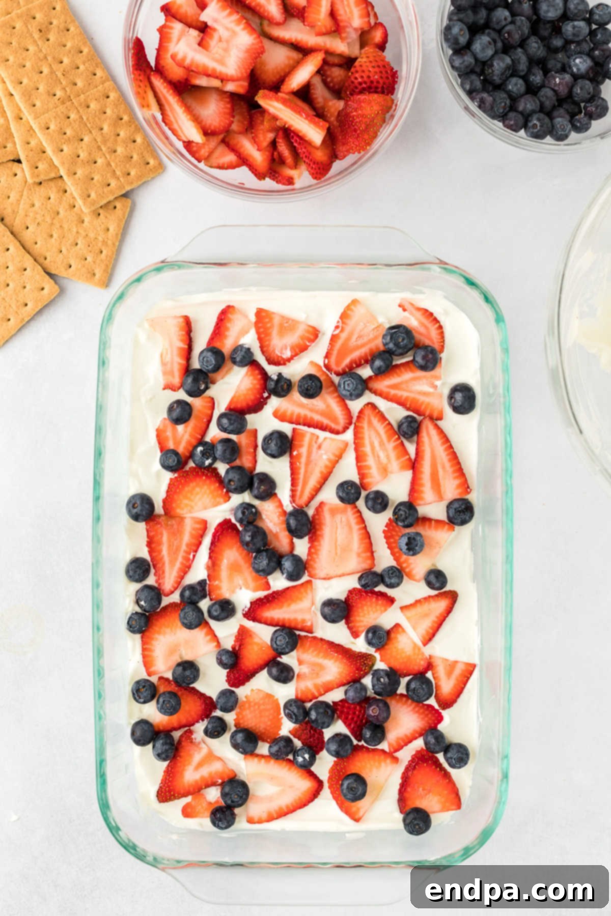 Fresh blueberries and thinly sliced strawberries are layered on top of the cream cheese mixture in a baking dish.