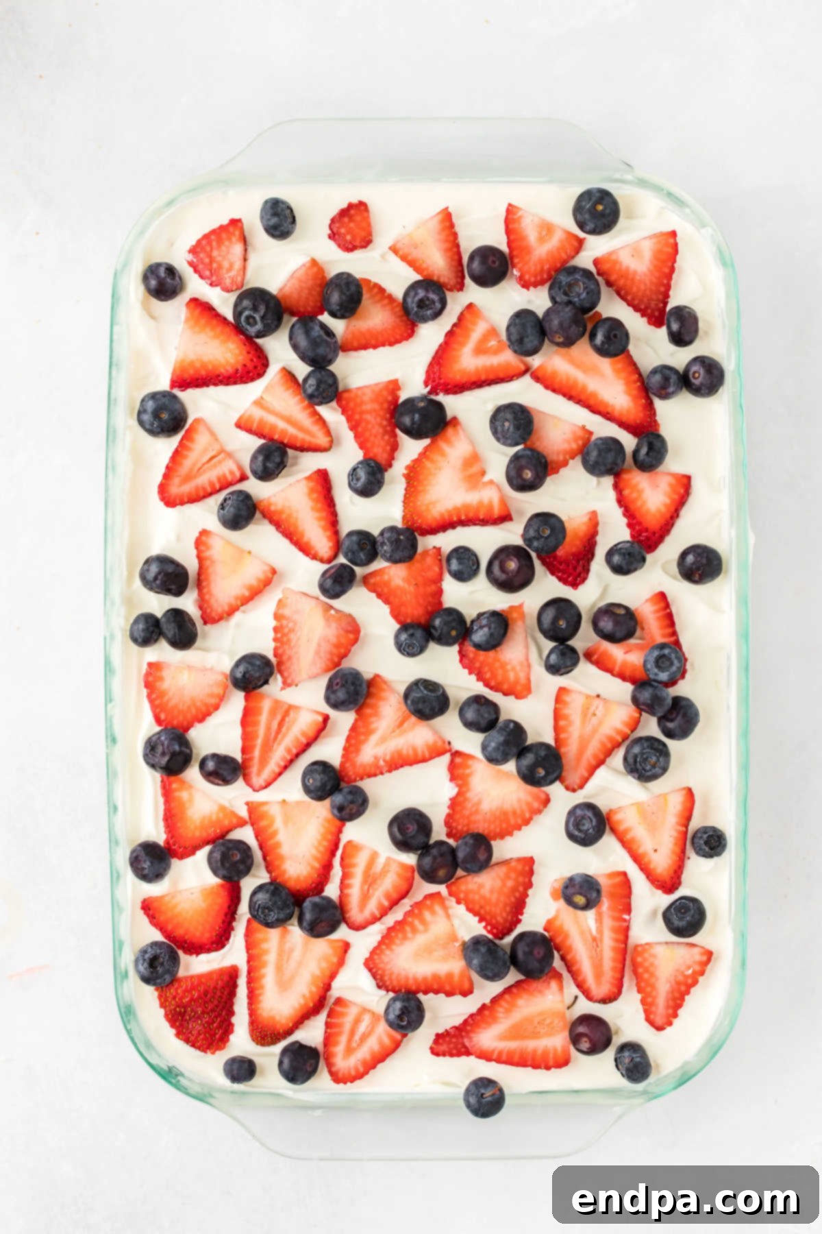 The top berry layer of the Red White and Blue Icebox Cake is decorated with an artistic scattering of strawberries and blueberries.