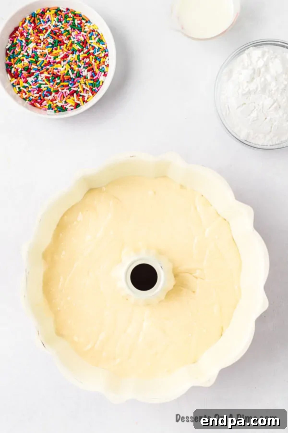 Velvet Ice Cream Cake 5 Smooth cake batter being poured from a mixing bowl into a prepared bundt cake pan, ready for baking.