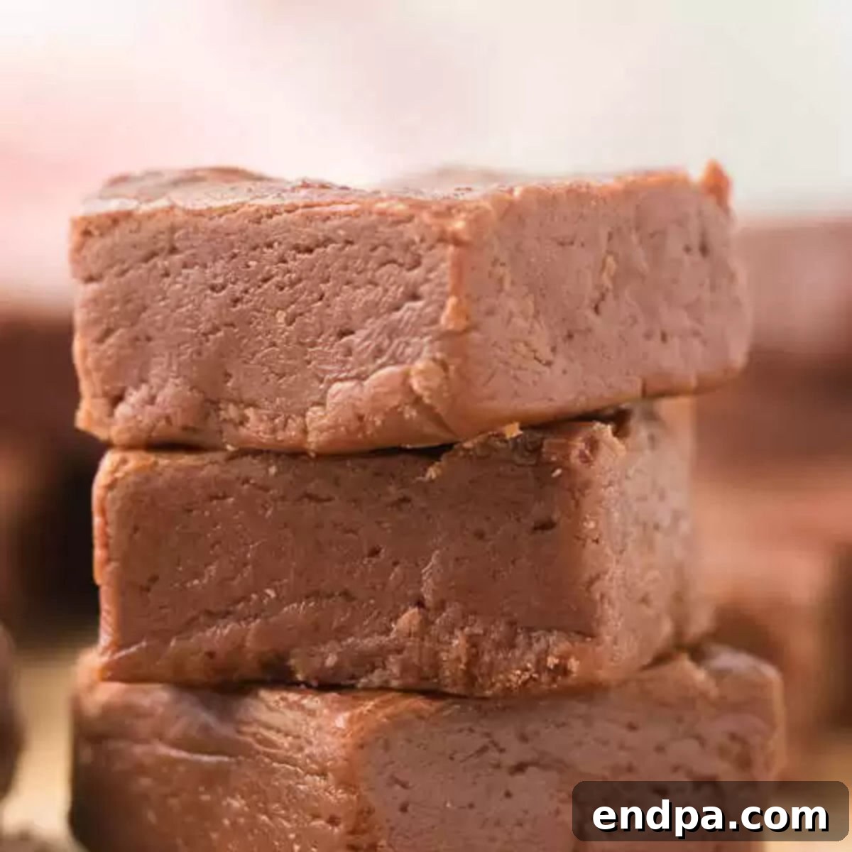 A collection of luscious homemade chocolate fudge squares, neatly arranged on a rustic wooden board, ready for indulgence.