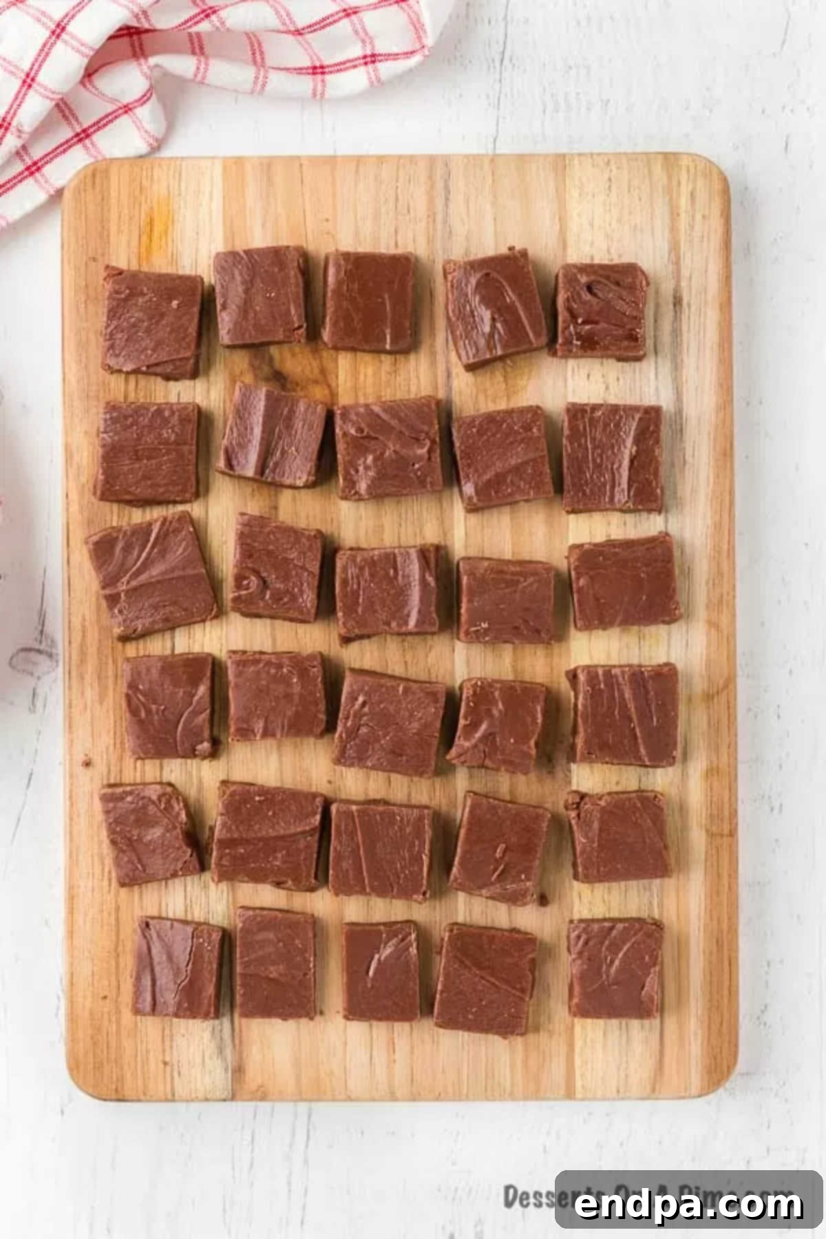 Exquisite squares of homemade chocolate fudge, neatly sliced and arranged on a cutting board, highlighting their perfect texture and rich color.