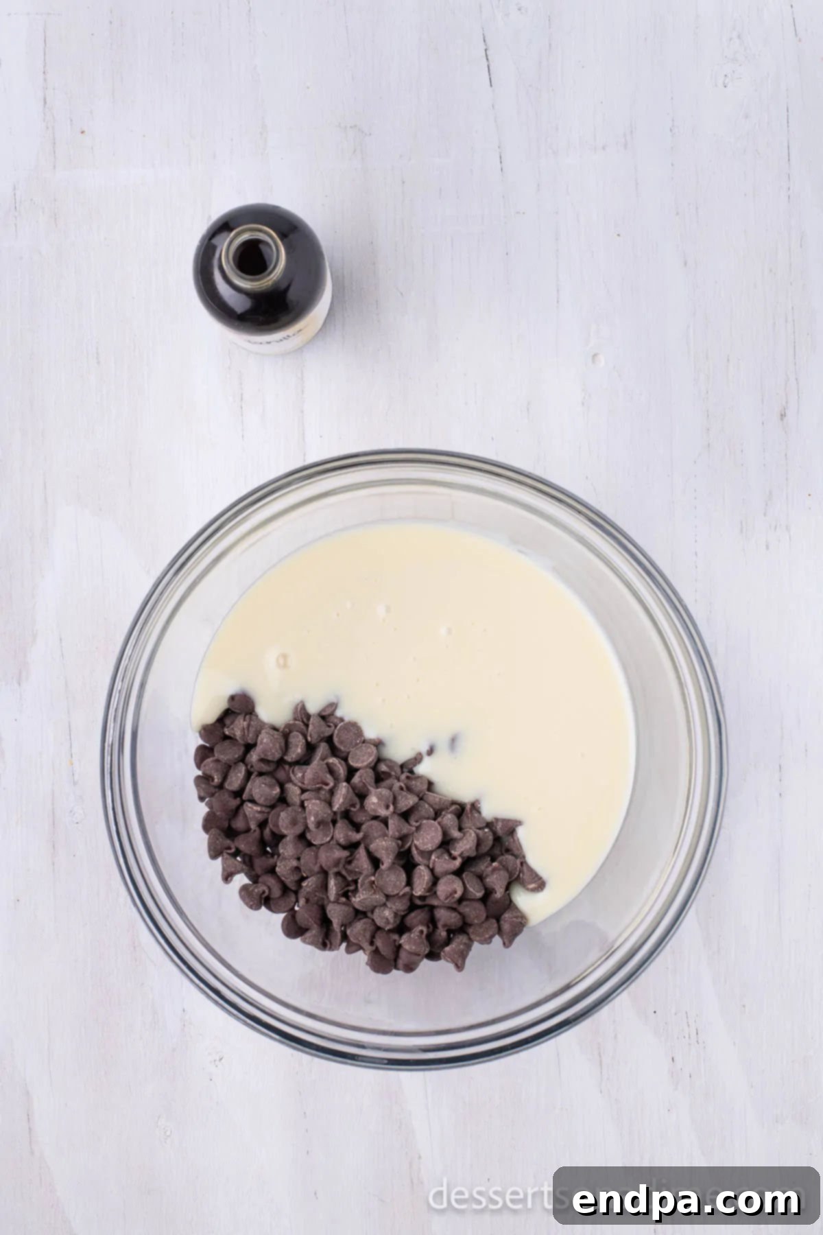 A microwave-safe bowl filled with semi-sweet chocolate chips and creamy sweetened condensed milk, ready for melting.