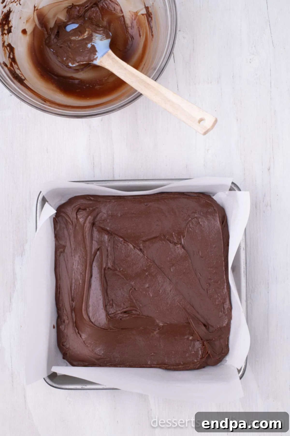 The evenly spread chocolate fudge mixture nestled in the pan, firming up in the refrigerator.