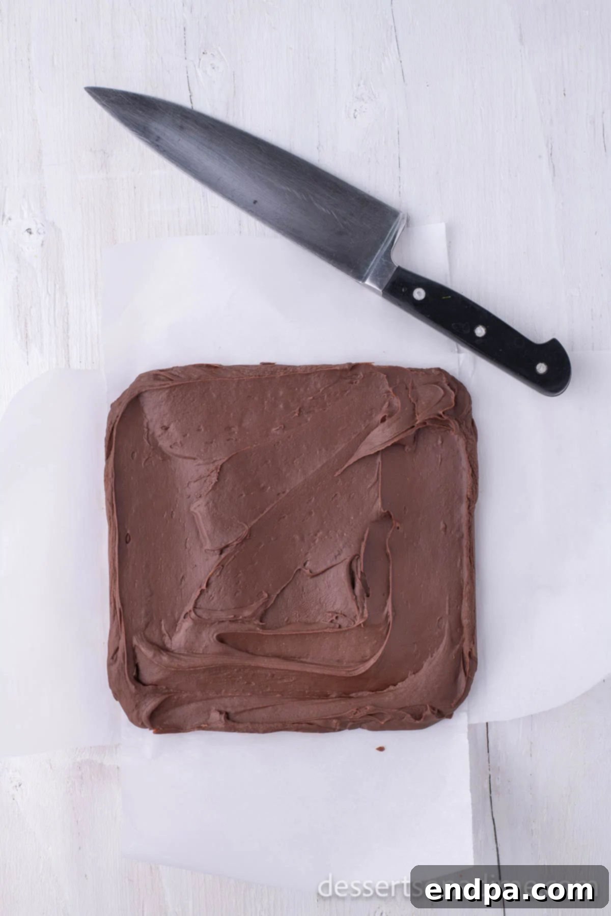 The perfectly set chocolate fudge, effortlessly lifted out of the pan using the parchment paper lining.