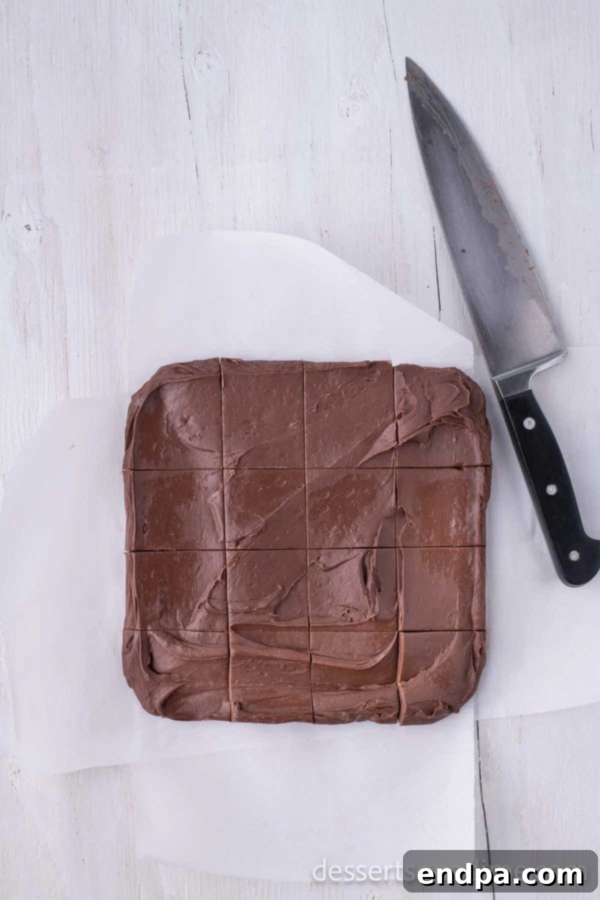 Precision-cut squares of homemade chocolate fudge, neatly arranged on a cutting board, showcasing their rich texture.
