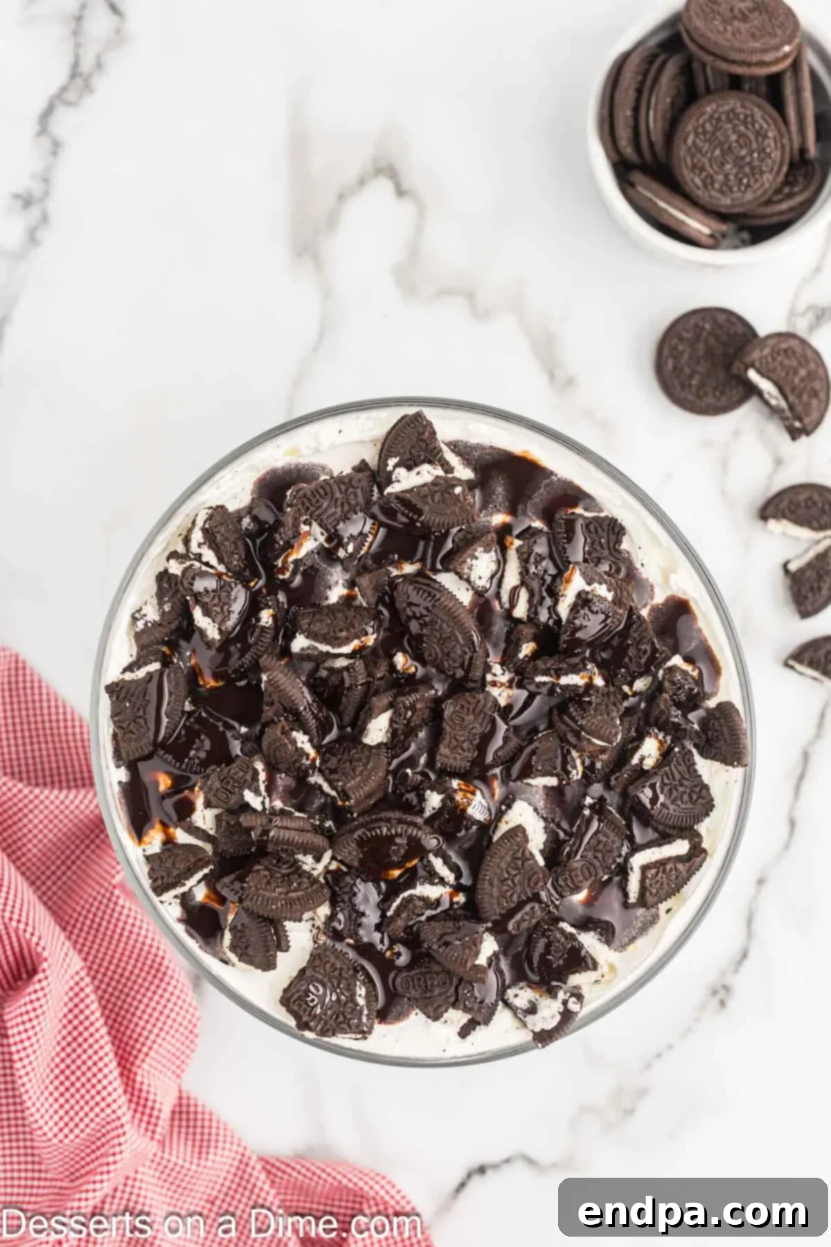 Oreo Dream Trifle 10 Layers in trifle dish topped with cookies and chocolate.