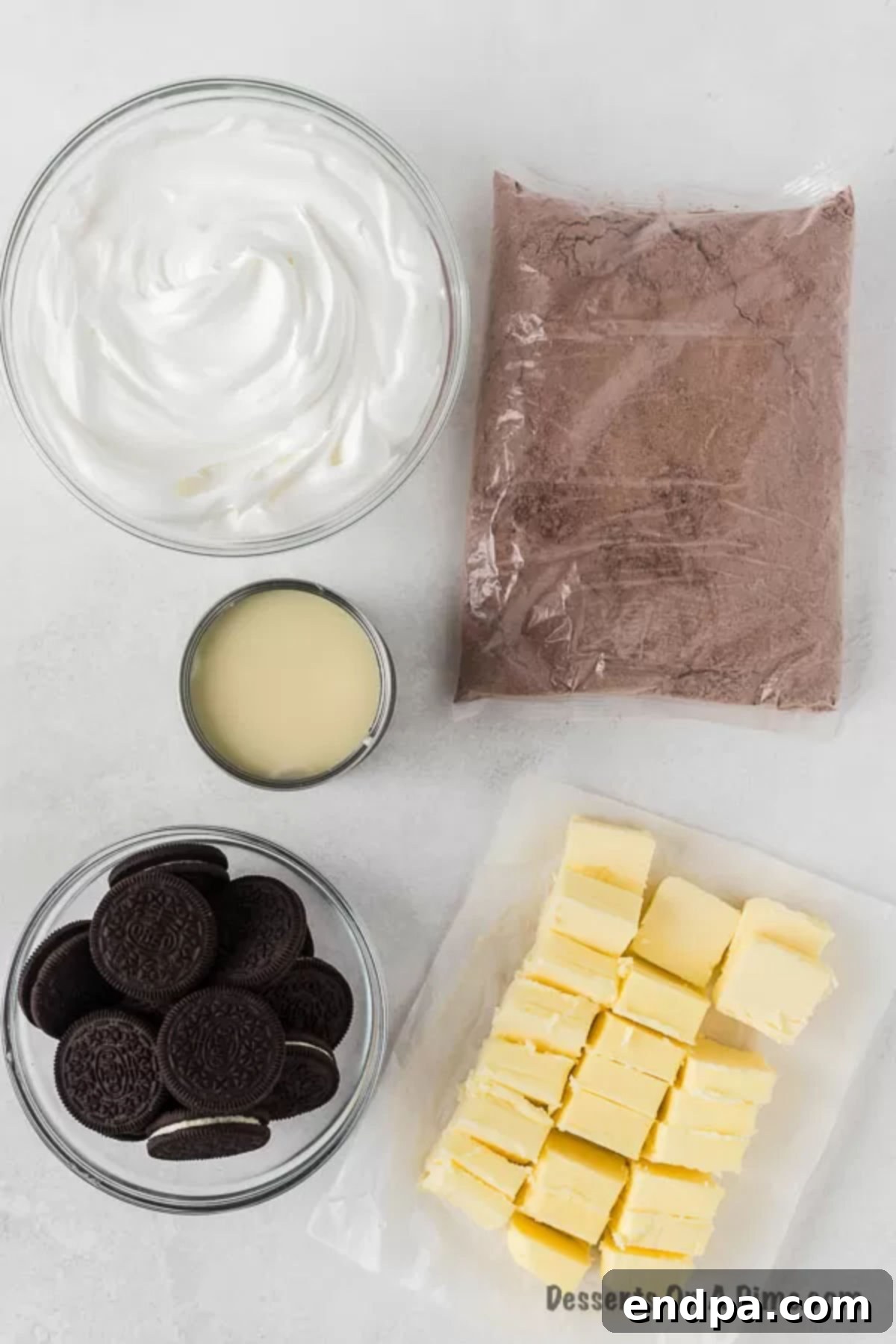 Irresistible Oreo Dump Cake 3 The five essential ingredients laid out for making Oreo Dump Cake: a pack of Oreo cookies, a can of sweetened condensed milk, a tub of Cool Whip, a box of chocolate cake mix, and sticks of butter.