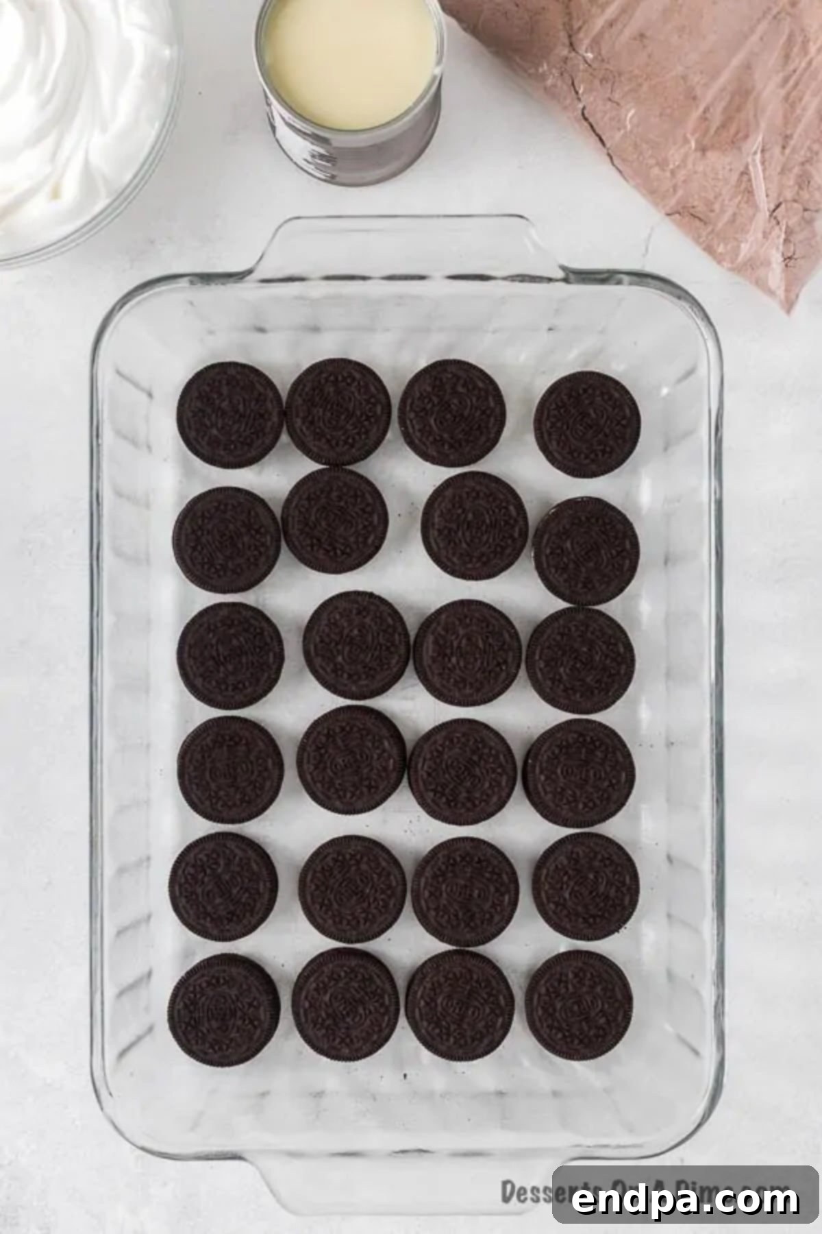 Irresistible Oreo Dump Cake 5 Oreo cookies meticulously arranged in a single, even layer at the bottom of a 9x13 inch baking pan, forming the delicious base of the dump cake.