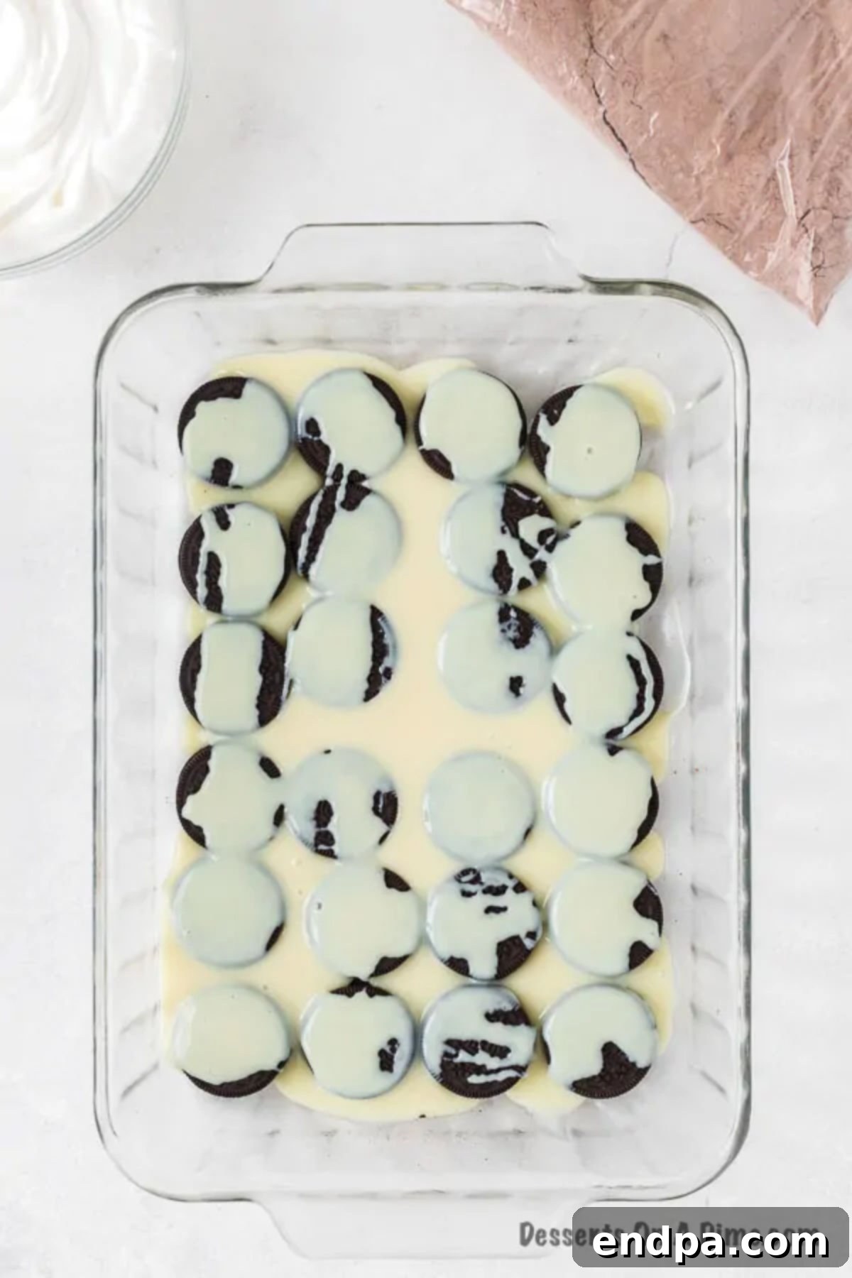 Irresistible Oreo Dump Cake 6 Sweetened condensed milk being smoothly and evenly poured over the vibrant layer of Oreo cookies in the baking pan, setting the stage for the next delicious component.