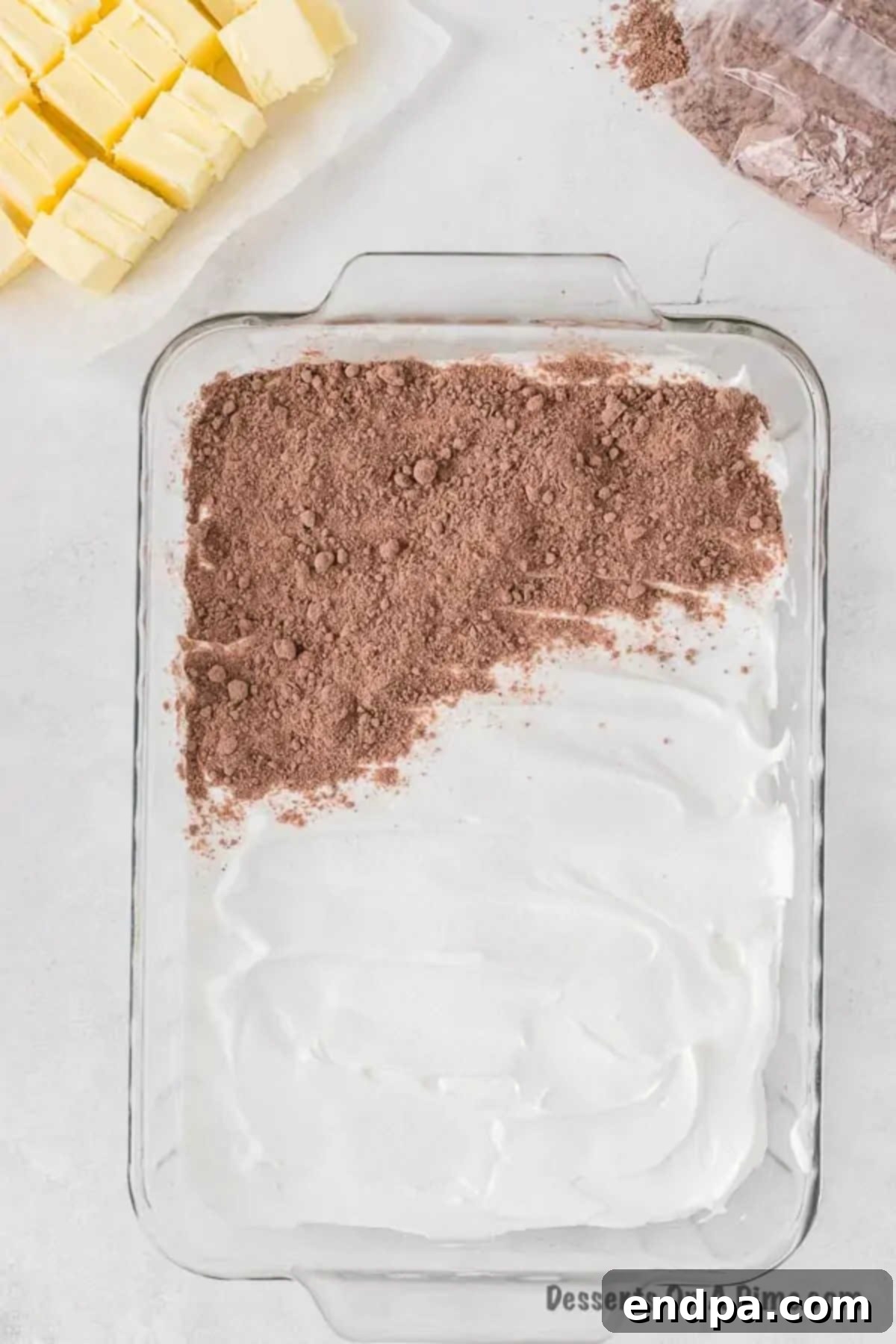 Irresistible Oreo Dump Cake 8 Dry chocolate cake mix being uniformly sprinkled over the Cool Whip layer in the baking pan, forming the crucial dry ingredient layer. No mixing required.