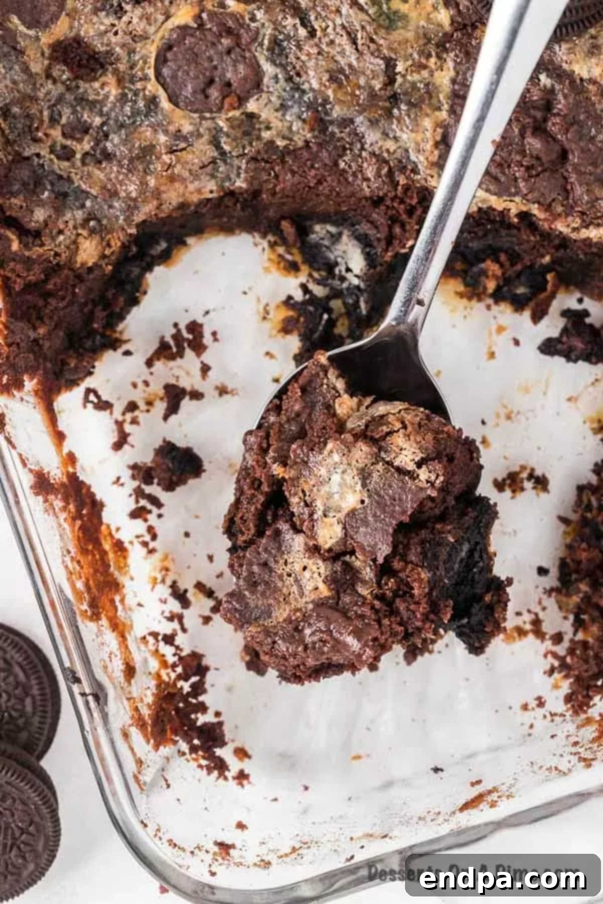Irresistible Oreo Dump Cake 10 A freshly baked and slightly cooled Oreo Dump Cake nestled in its 9x13 inch pan, with a serving spoon poised to scoop out a warm, gooey, and inviting portion for dessert.