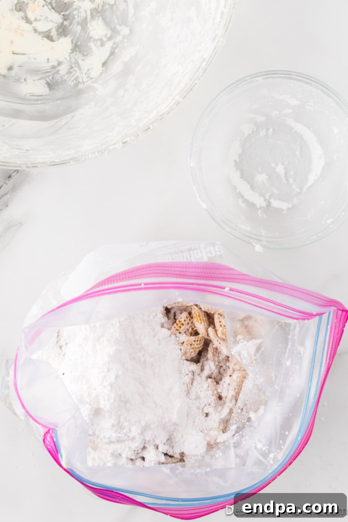 Cereal mixture added to a Ziploc bag with powdered sugar.