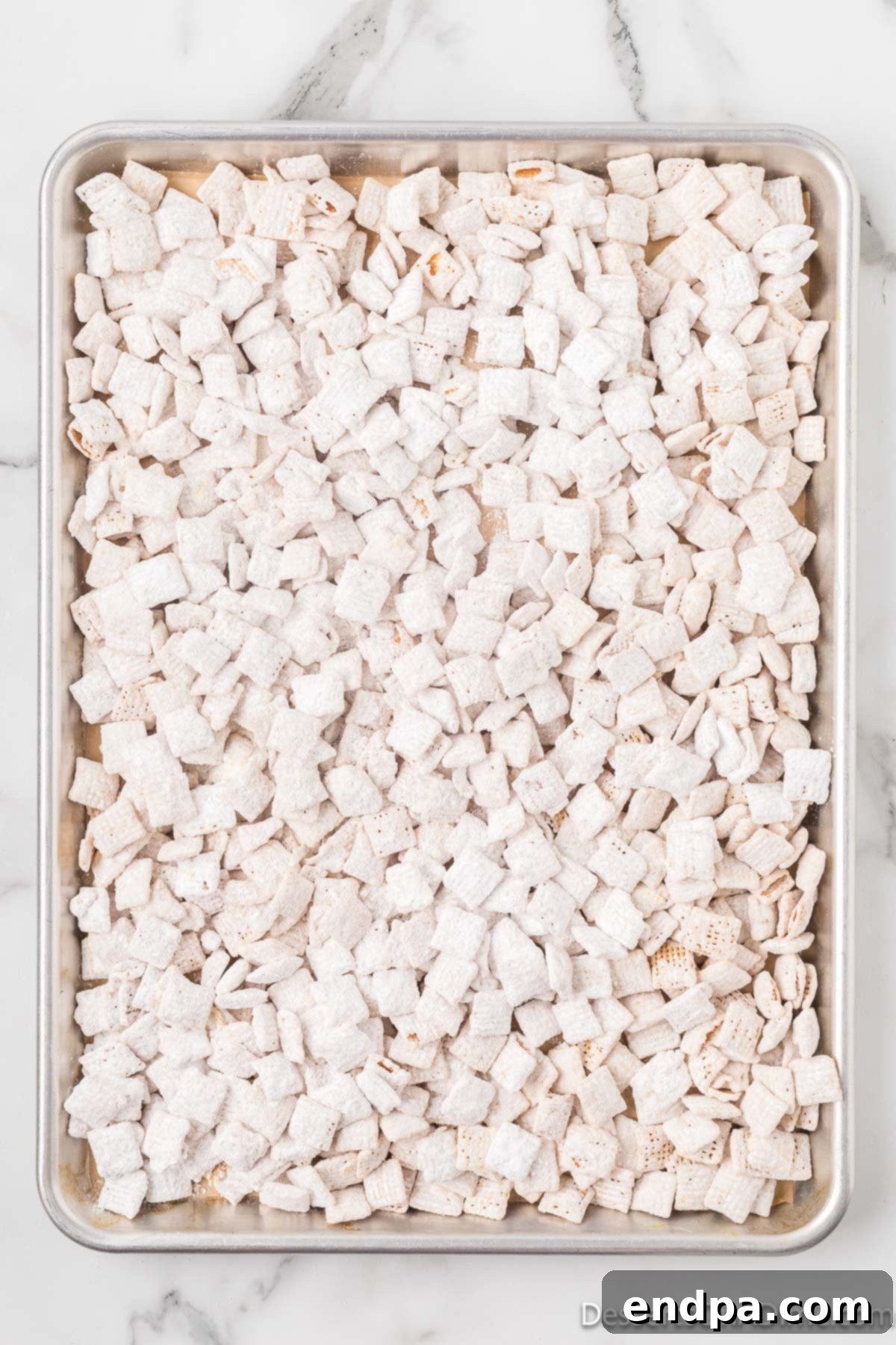 Lemon puppy chow spread out on a baking sheet to cool.