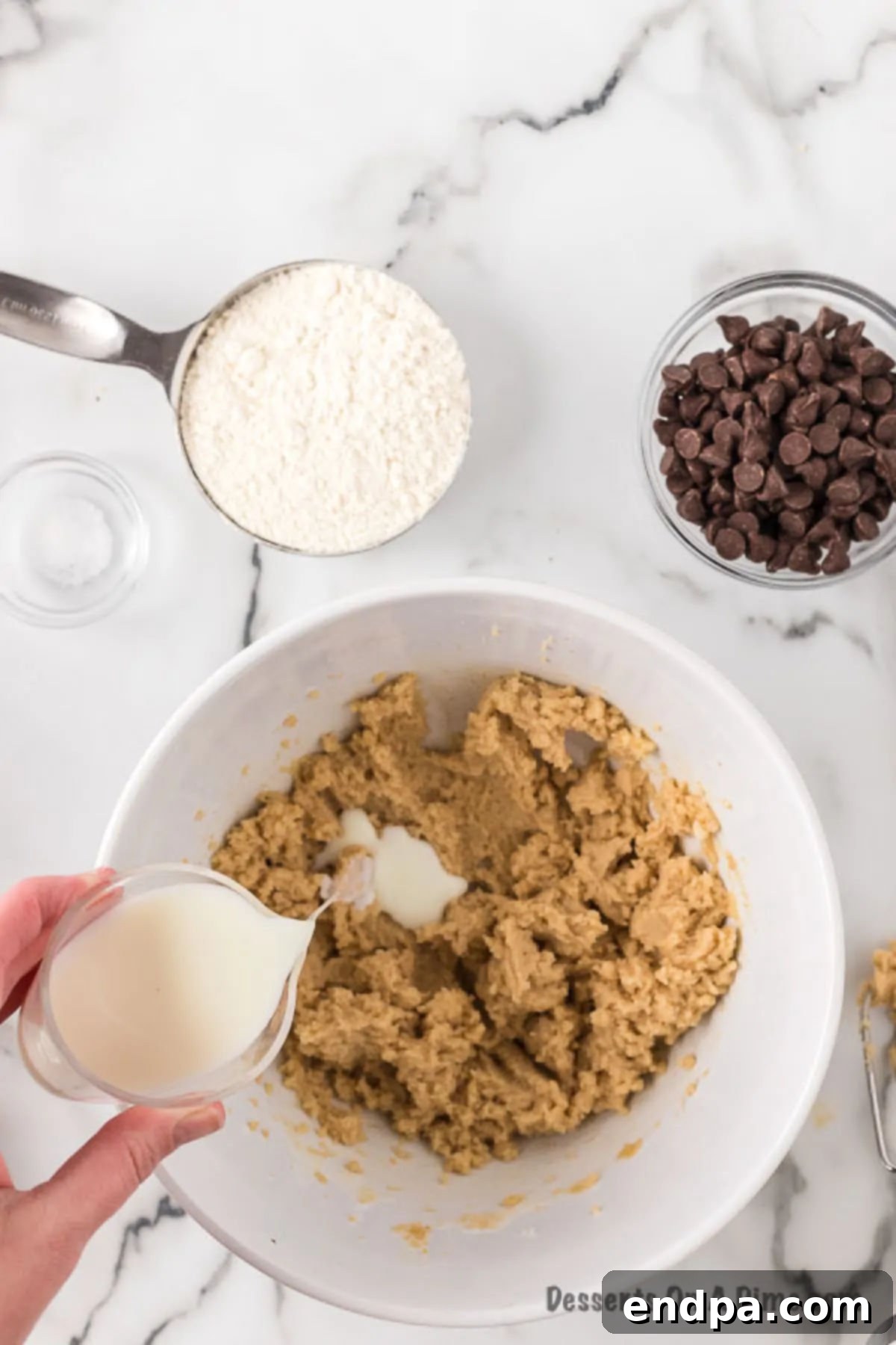 Ready-to-Eat Cookie Dough Dream 5 Milk being added to the creamed butter and sugar mixture in a bowl, before being mixed further.