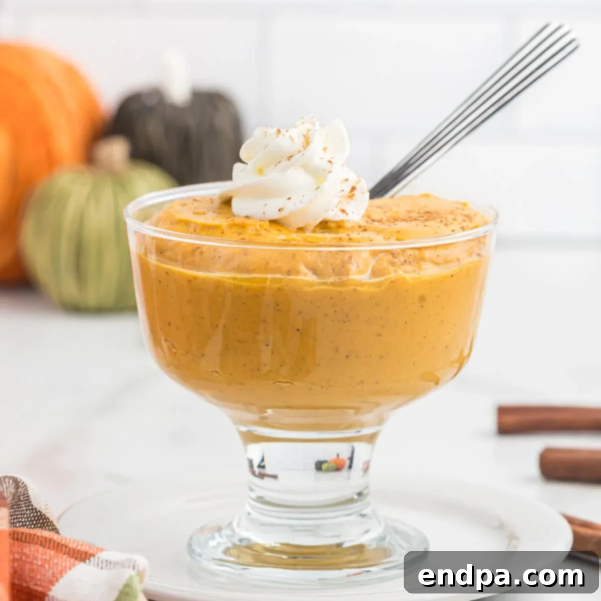 Spiced Pumpkin Dream 11 Pumpkin pudding in a glass dish, topped with whipped cream.