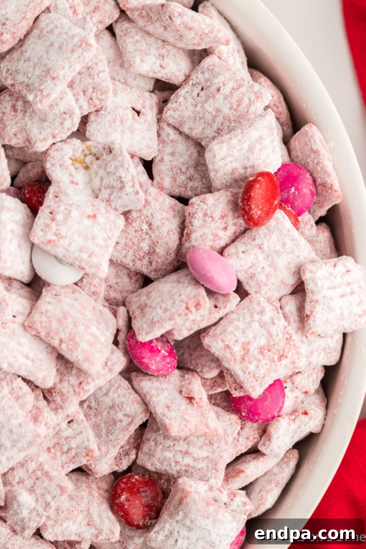 Valentine's Day Puppy Chow in a white bowl, adorned with festive M&Ms.